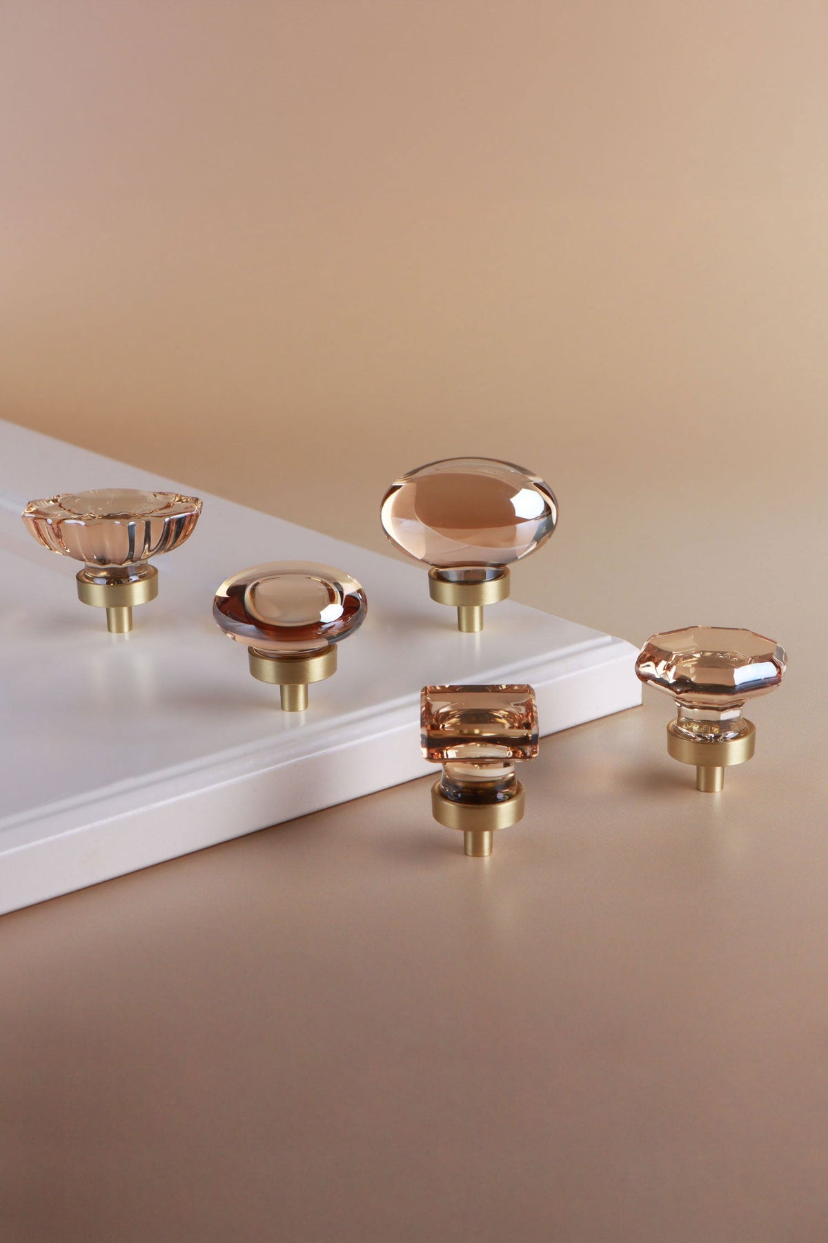 Five champagne crystal glass cabinet knobs with satin brass bases, shown together
