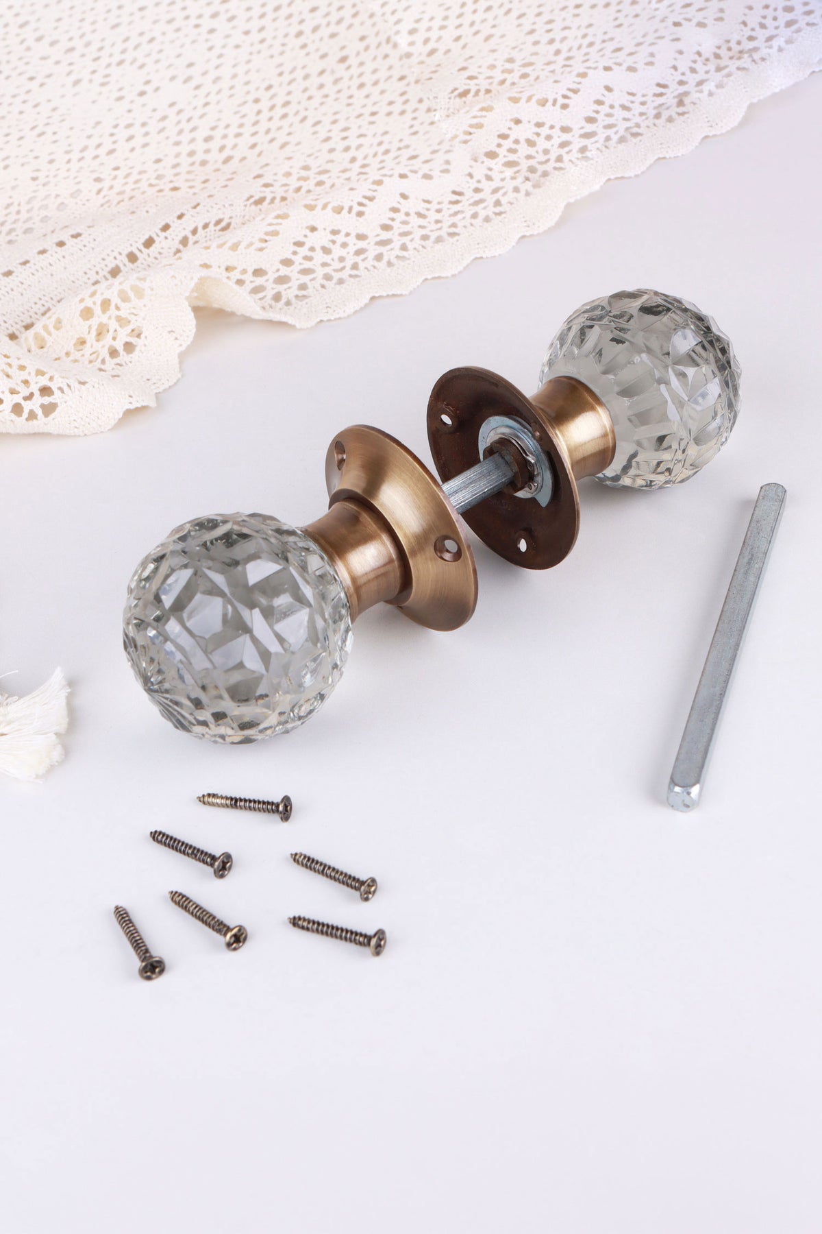 Clear Crystal glass mortice door knobs joined by the spindle through their antique brass roses, as they sit on a door