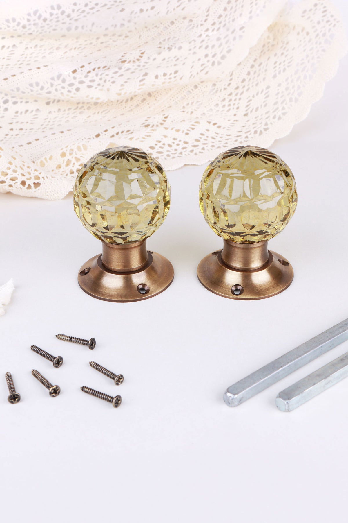 Pair of ivory faceted glass mortice door knobs on antique brass roses, with the square spindles and fixing screws