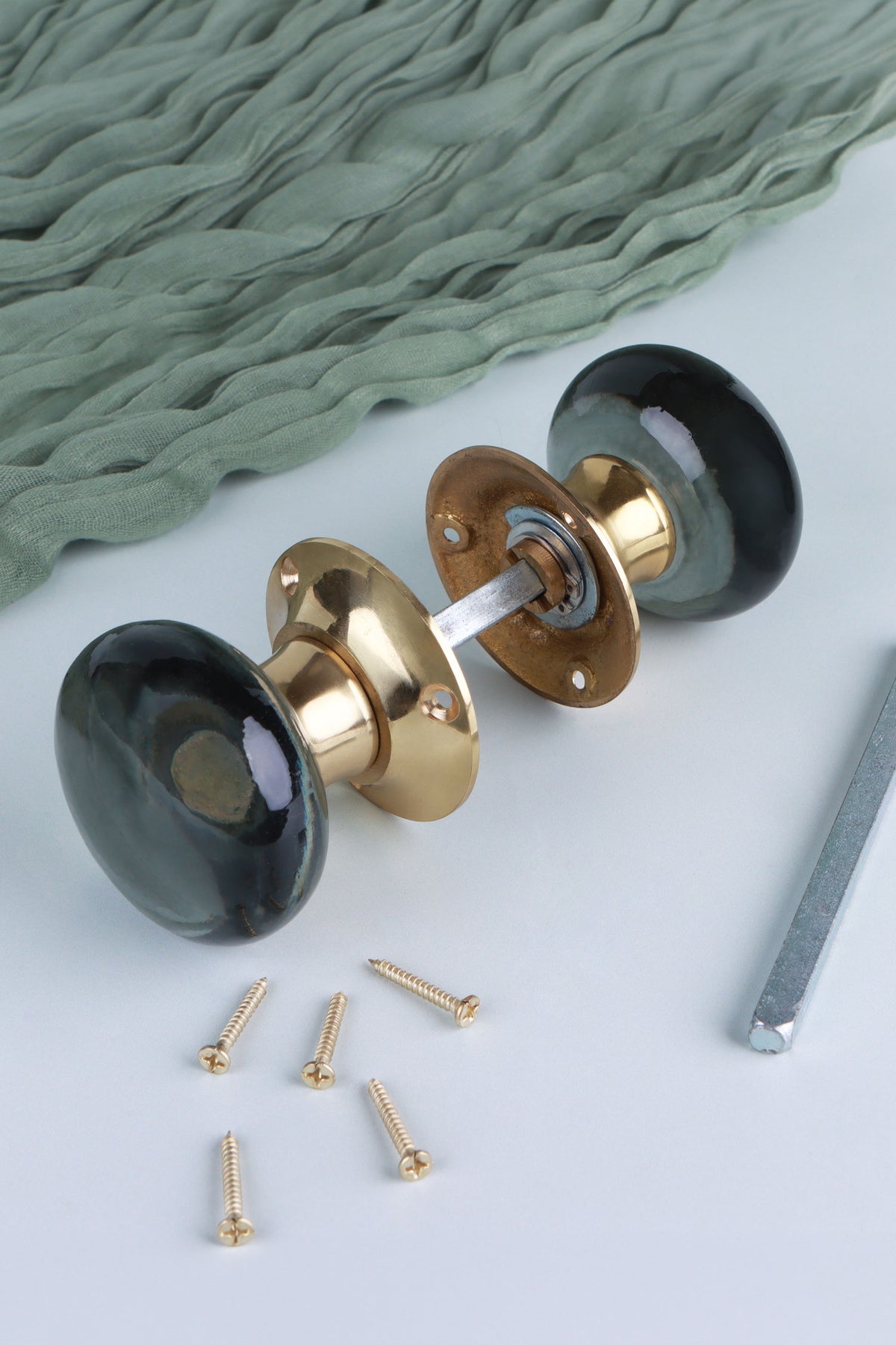 Smokey grey glass dome mortice door knobs joined by the spindle through their polished brass roses, as they sit on a door