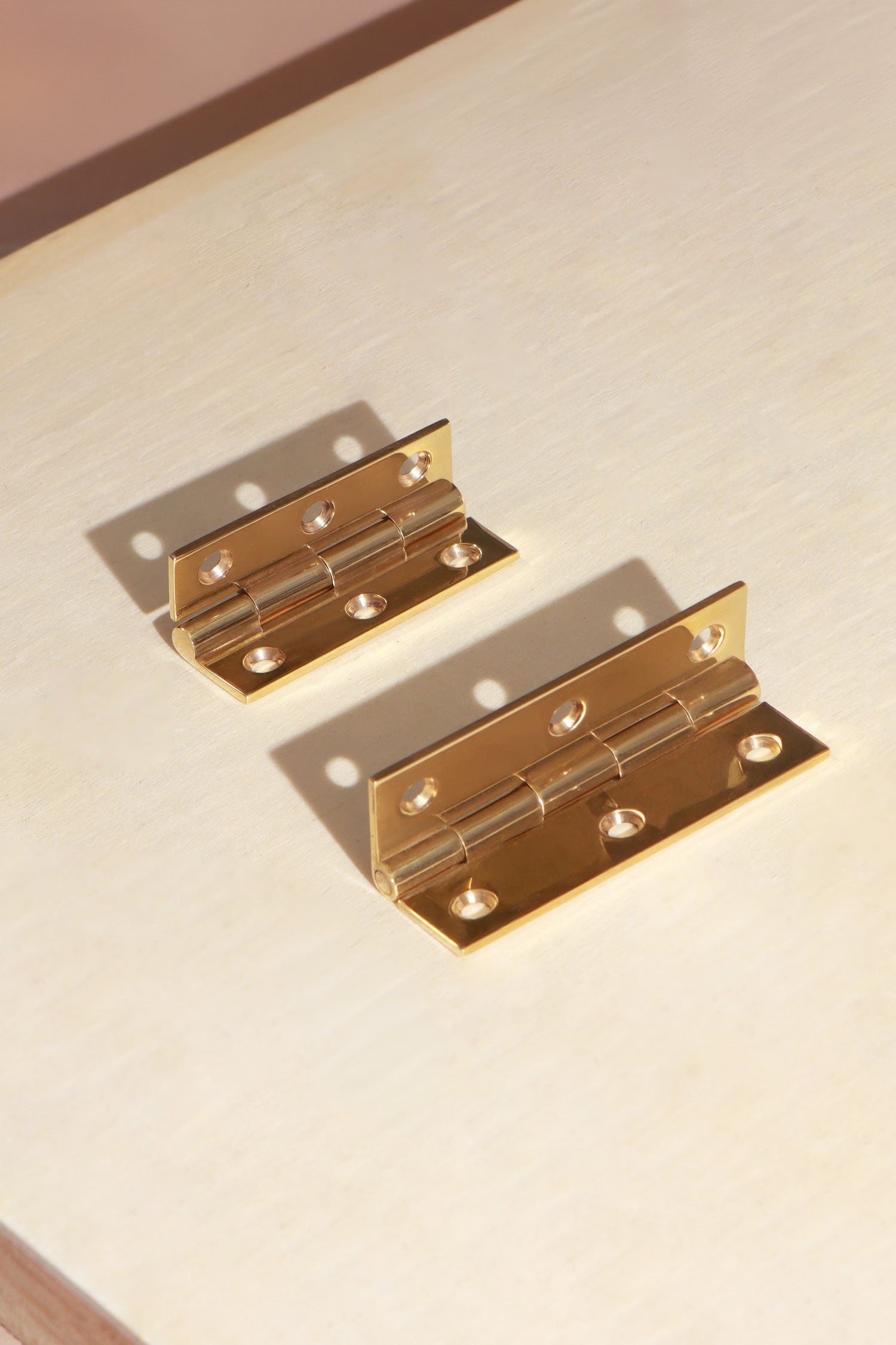 Polished brass butt hinge open, showing the knuckle and solid brass screws