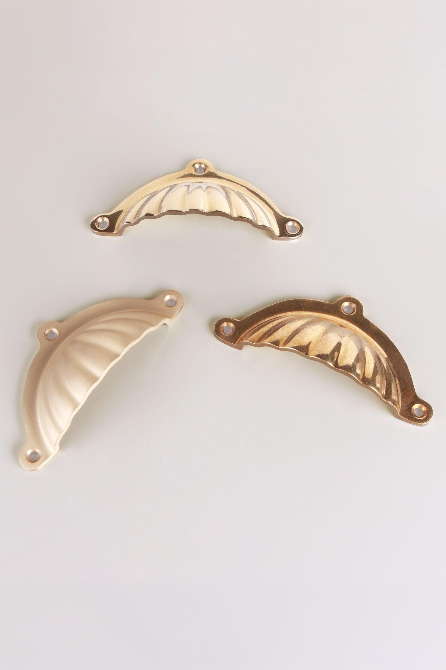 Scalloped cup pulls on a drawer front, ribs catching the light