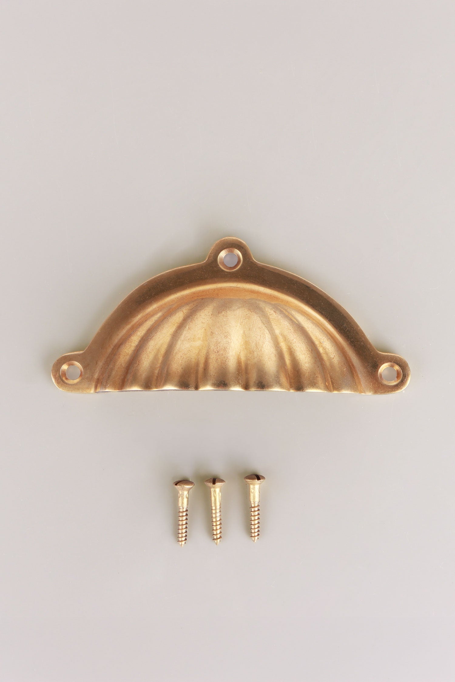 Scalloped cup pull in aged brass, unlacquered living finish