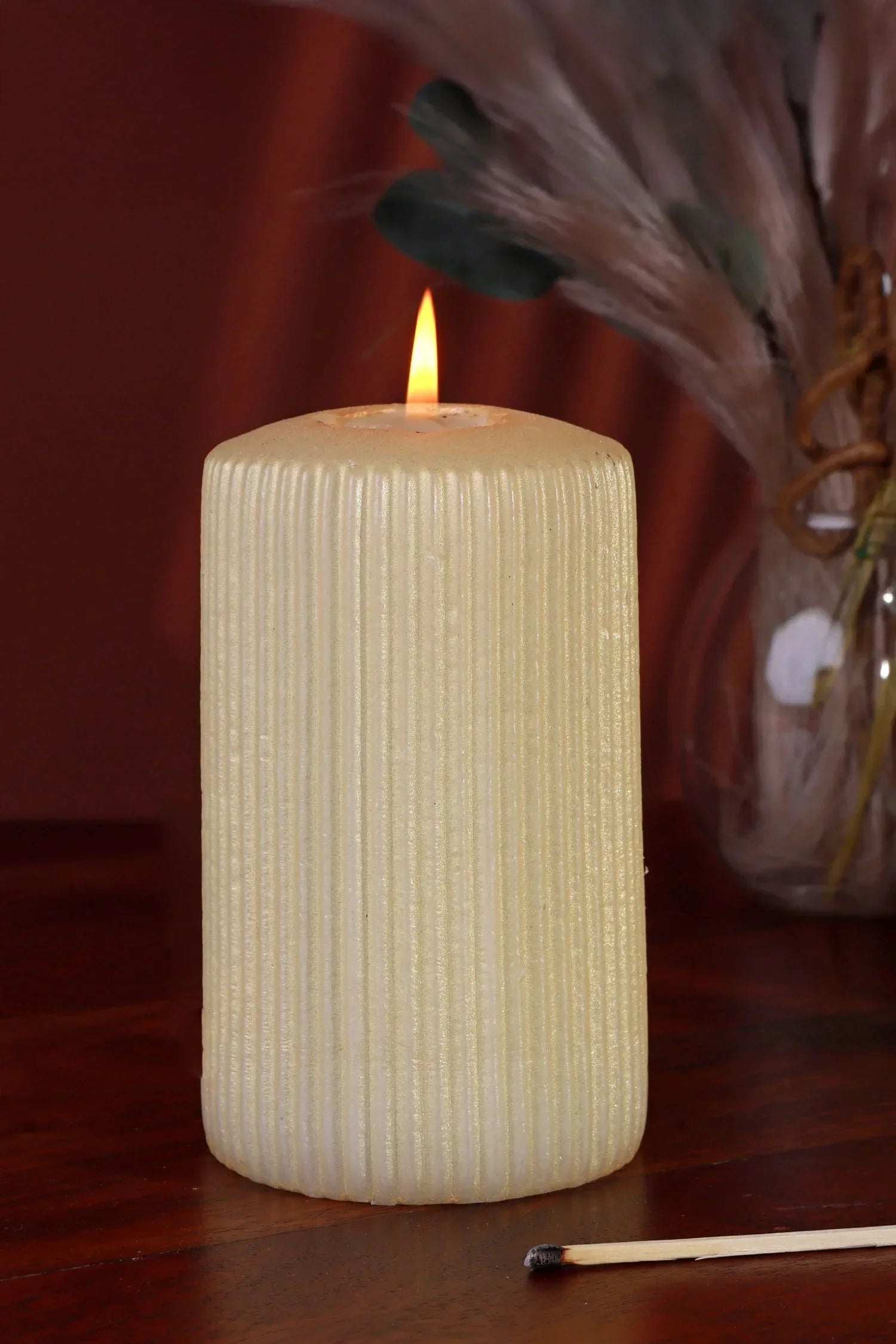 Textured ivory pillar candle by G Decor on wooden table with vase and matchstick
