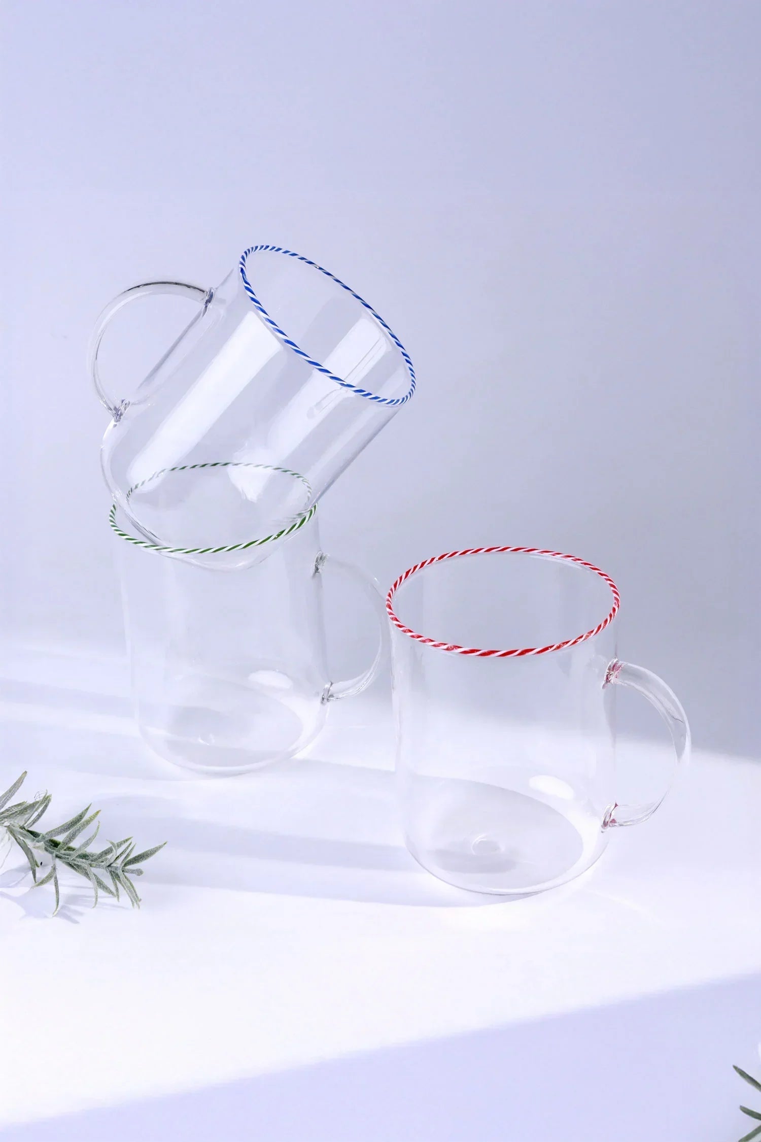 Clear glass mugs with red, green, and blue striped rims by G Decor on a white background