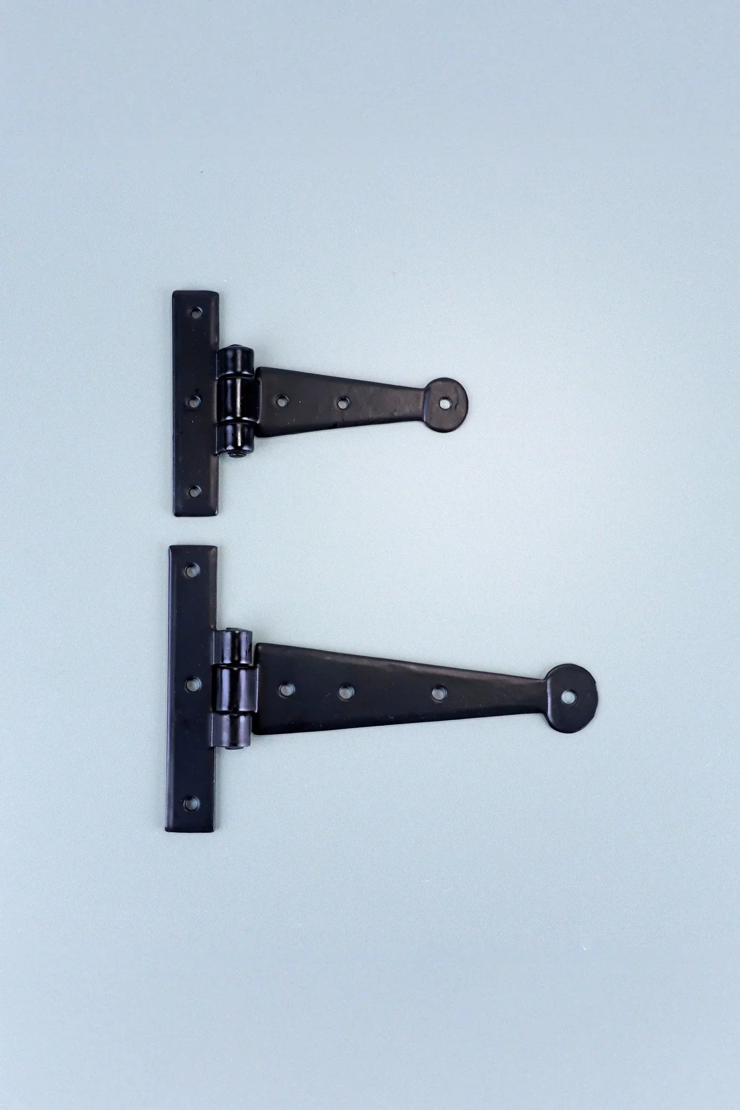 Two black metal T hinges for doors or cabinets on a light background, G Decor hardware