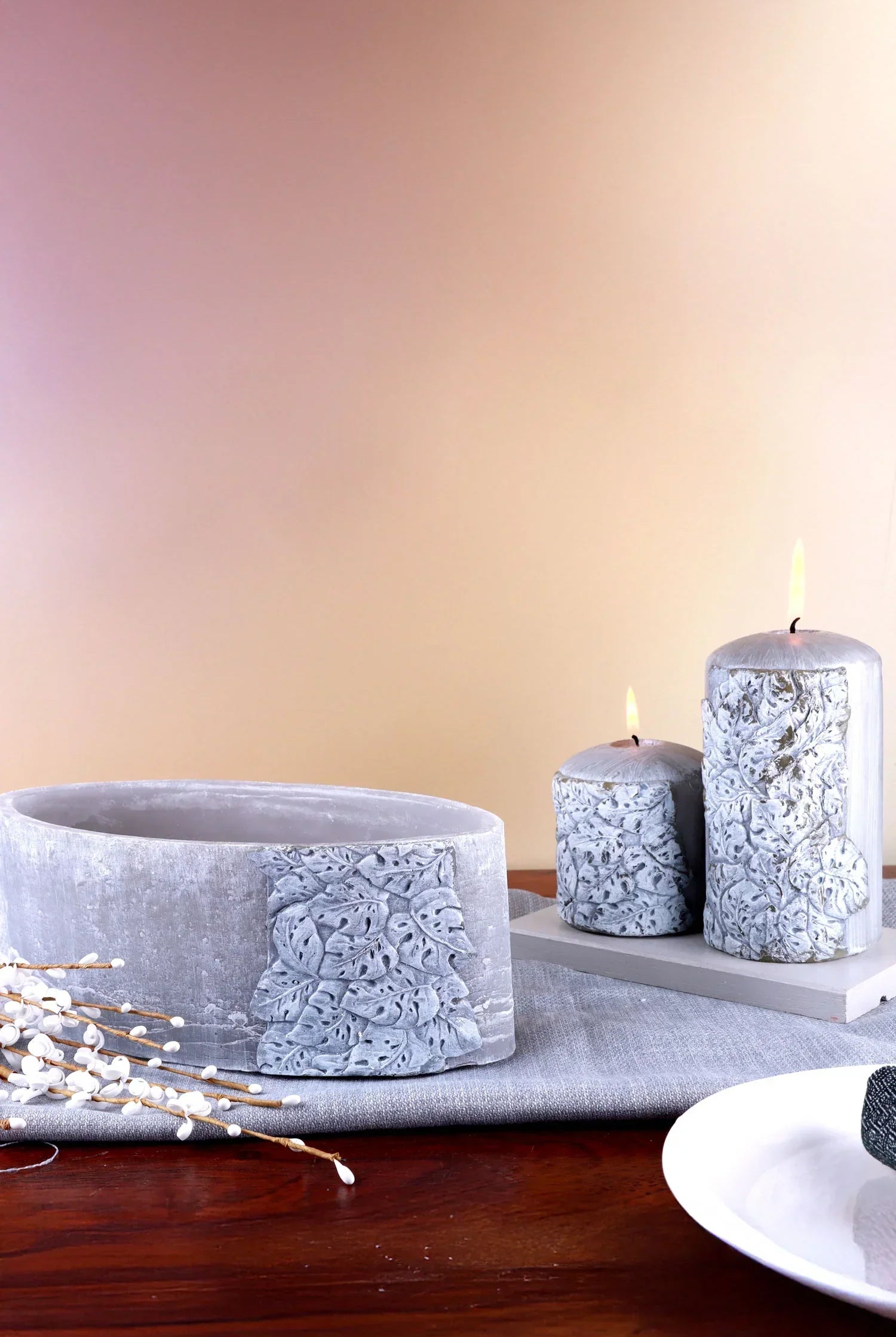 Decorative grey candles and bowl with embossed leaf design on wooden table, G Decor
