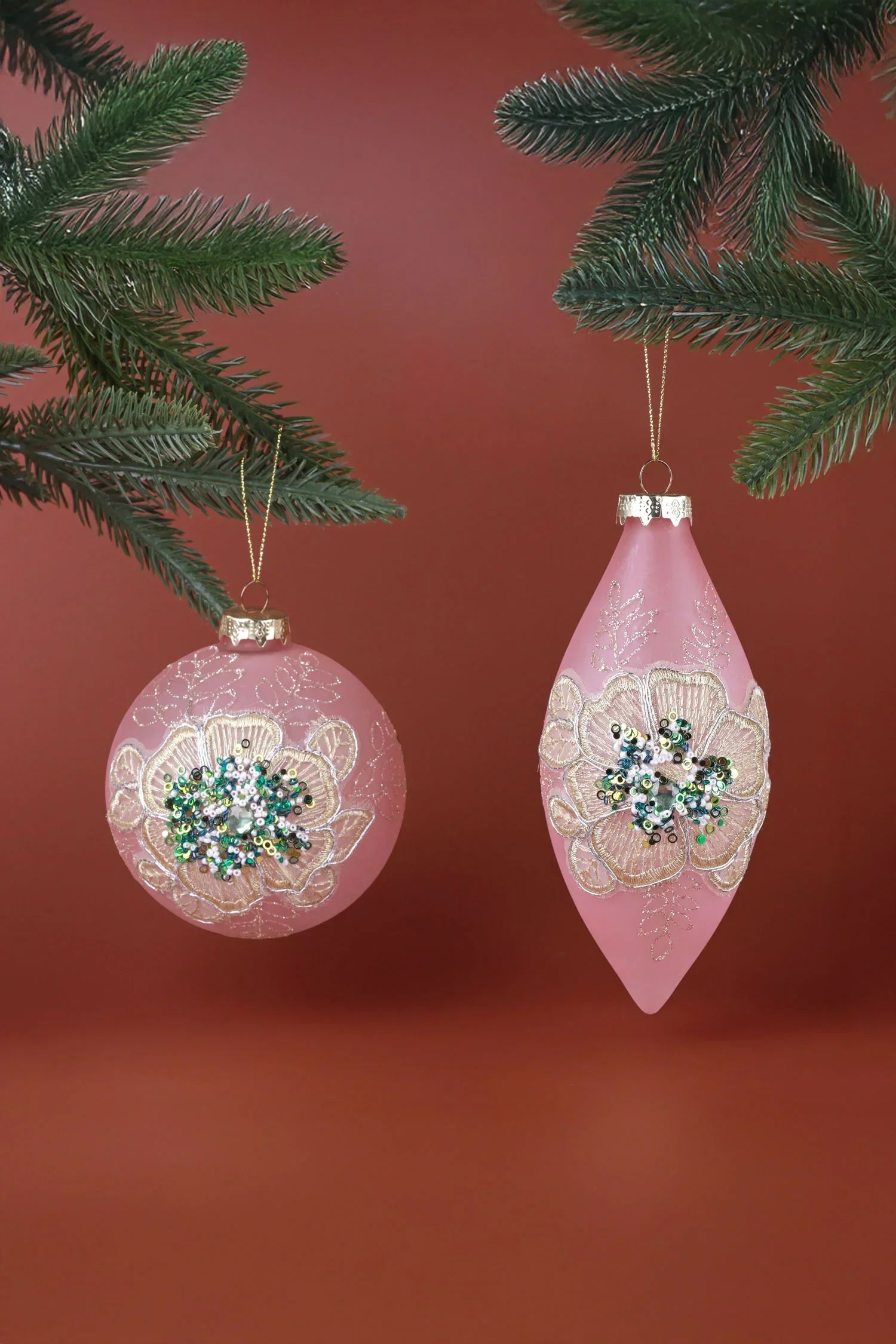 Pink luxury Christmas ornaments with gold floral designs and sequins on pine branches