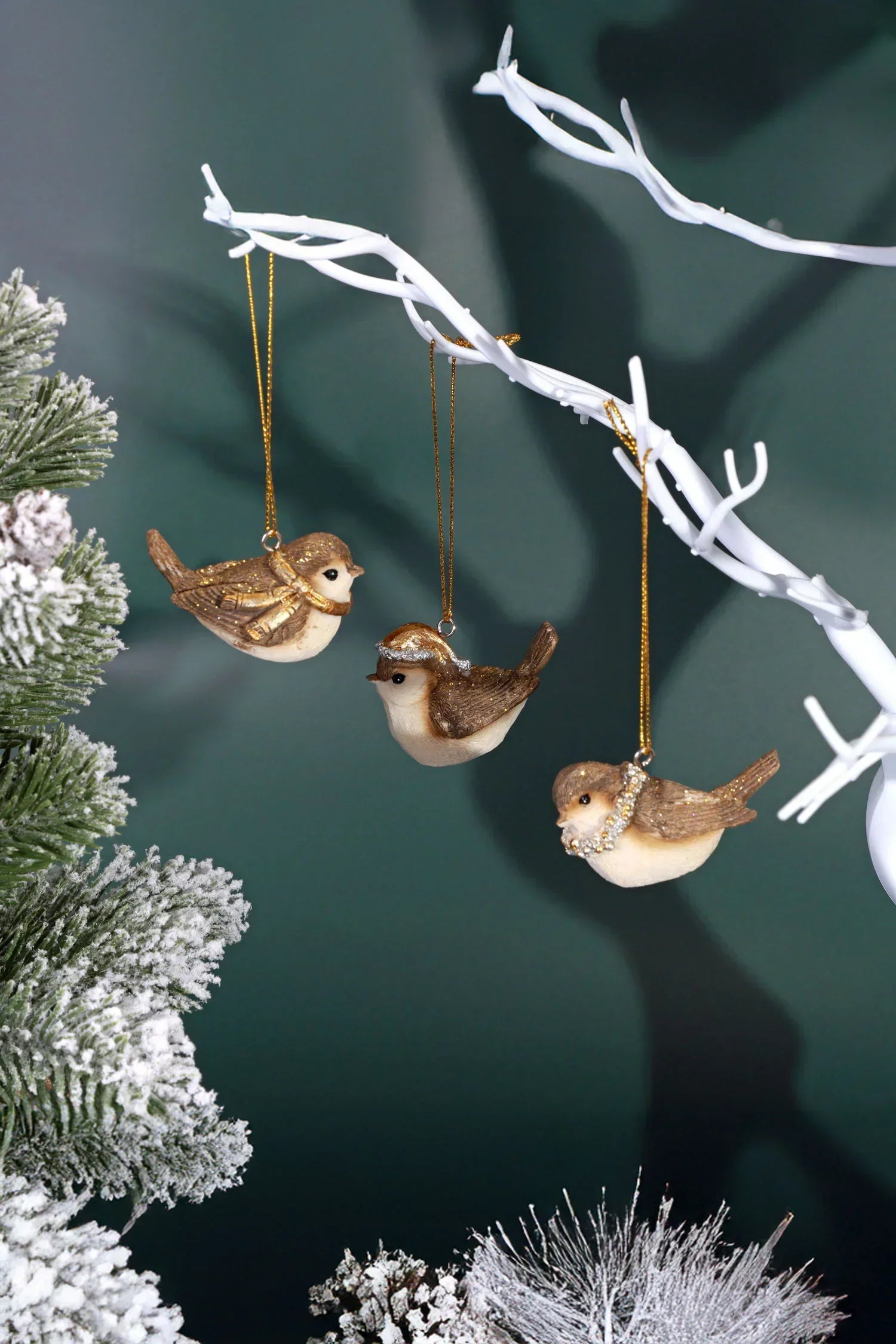 Glitter bird ornaments hanging on white branches, snow-dusted pine, luxury G Decor holiday décor