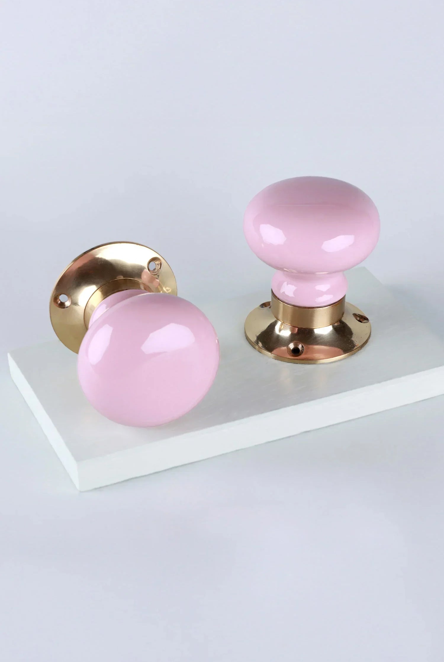 Pair of G Decor luxury pink ceramic and gold door knobs on white background