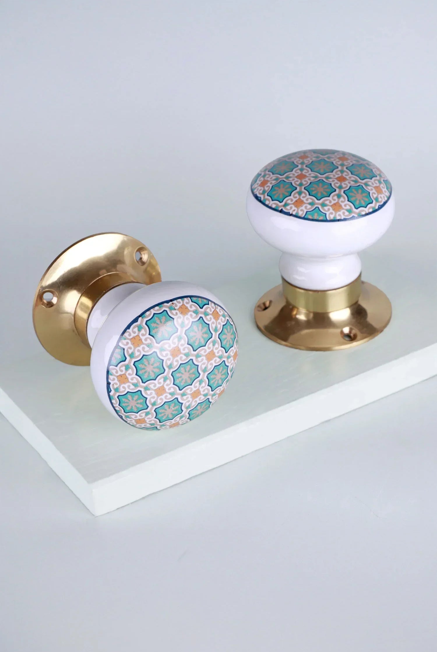 Pair of G Decor luxury ceramic and brass door knobs with blue geometric pattern on white background