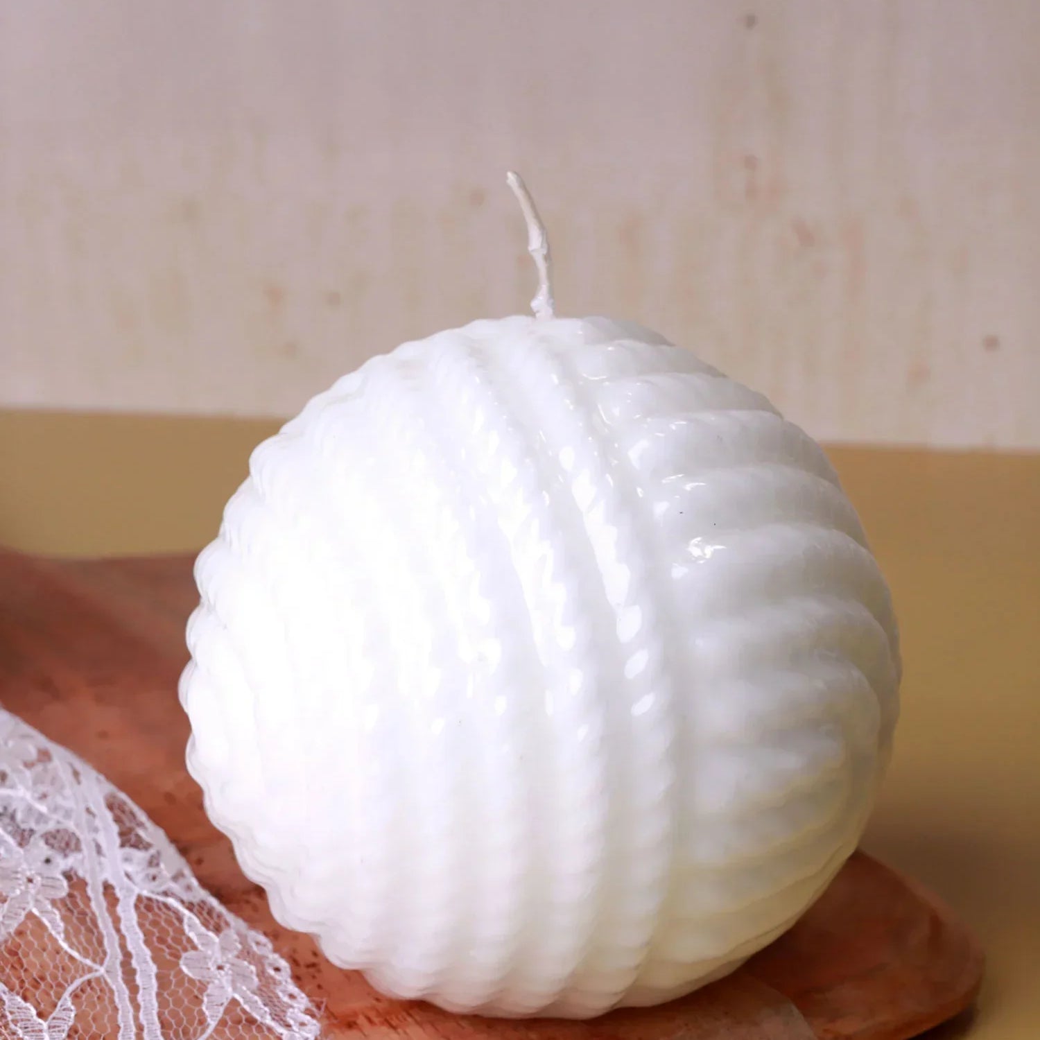 Textured white round candle on wooden tray, lace fabric accent, luxury home décor