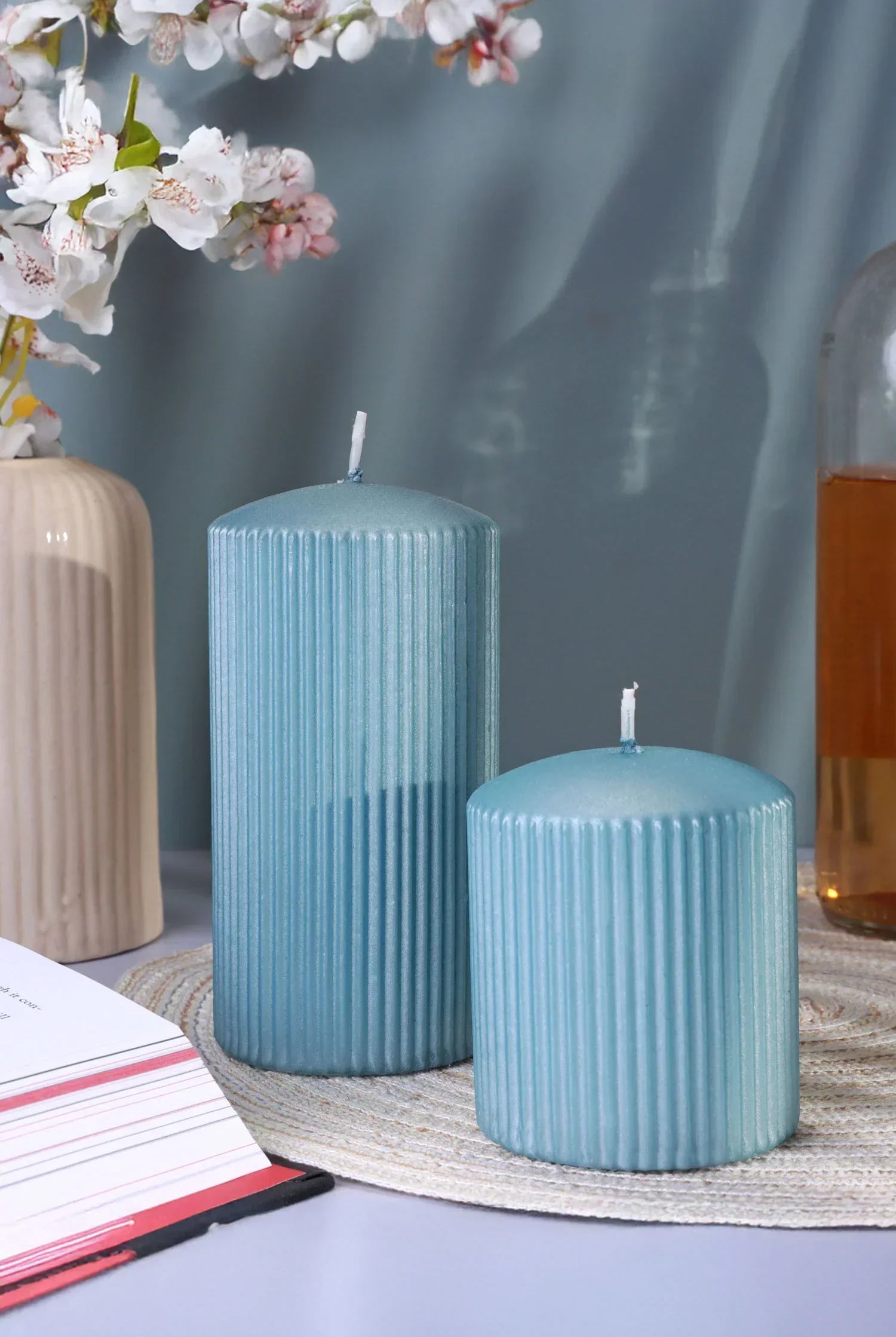 Blue ribbed pillar candles on a table with decor, floral vase, and glassware by G Decor