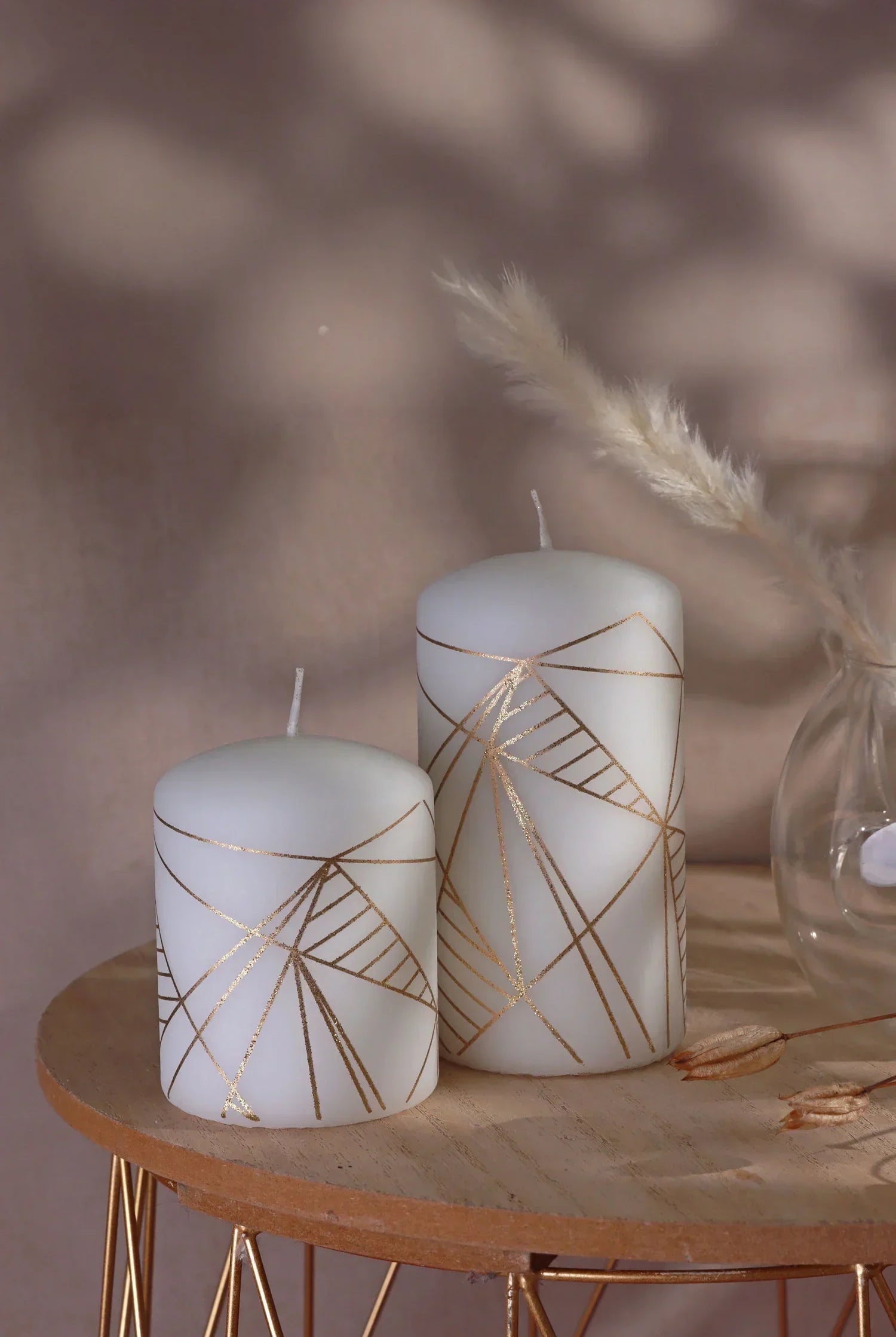 White pillar candles with gold geometric lines on a wooden table, luxury home décor by G Decor