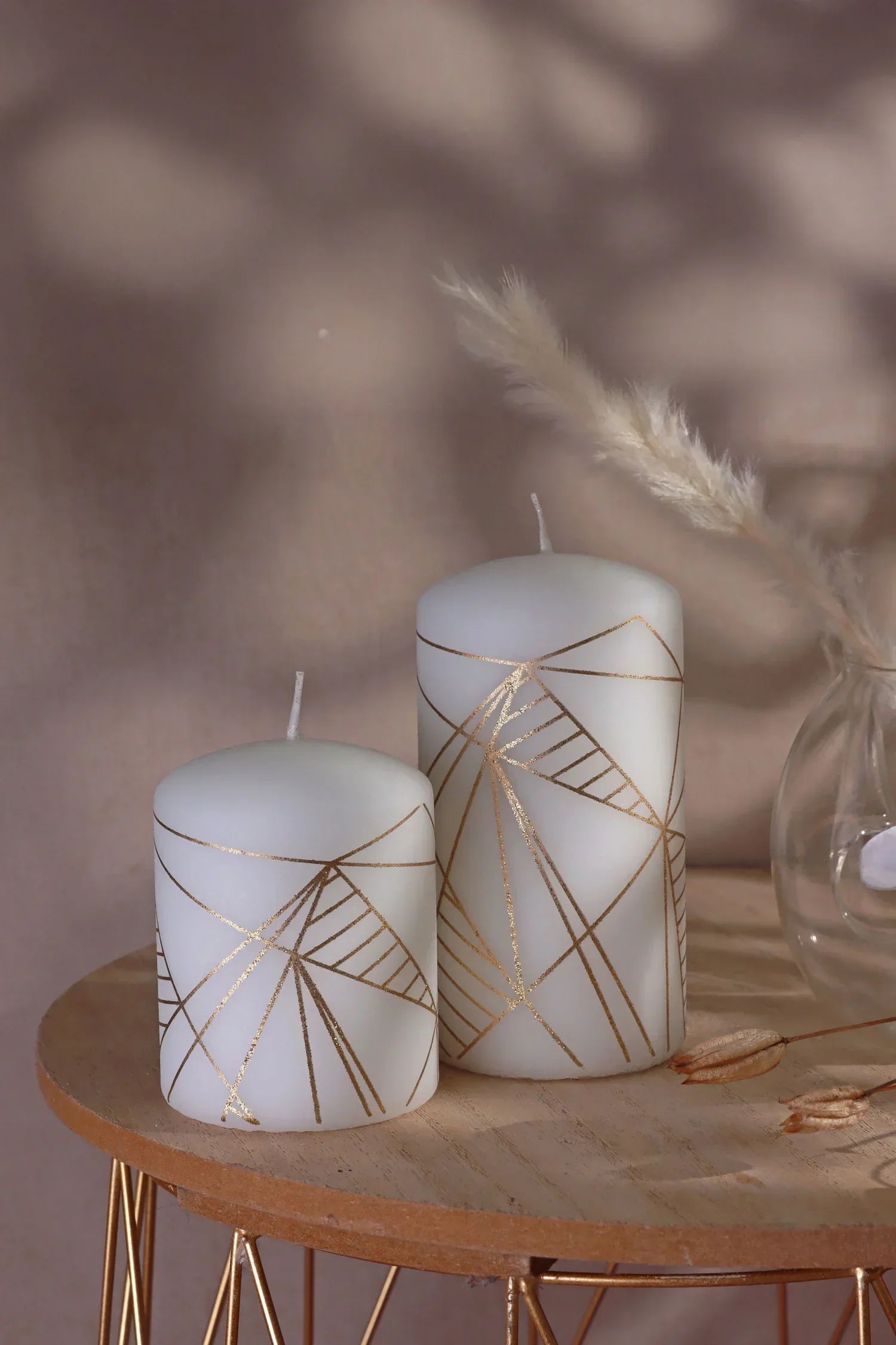 White pillar candles with gold geometric lines on a wooden table, luxury home décor by G Decor