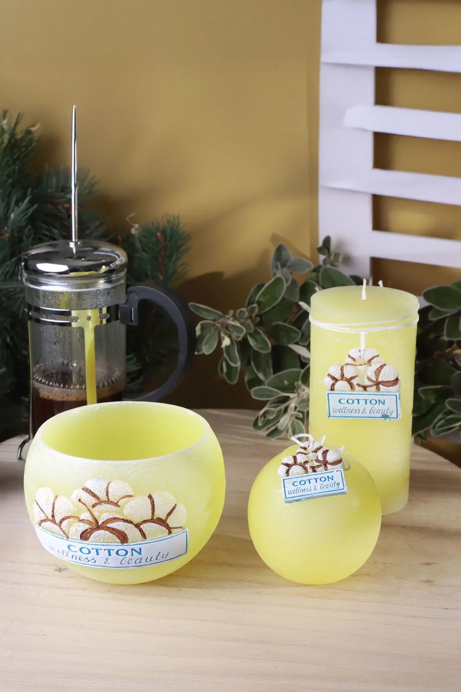 Yellow cotton wellness candles by G Decor on wooden table with greenery and French press
