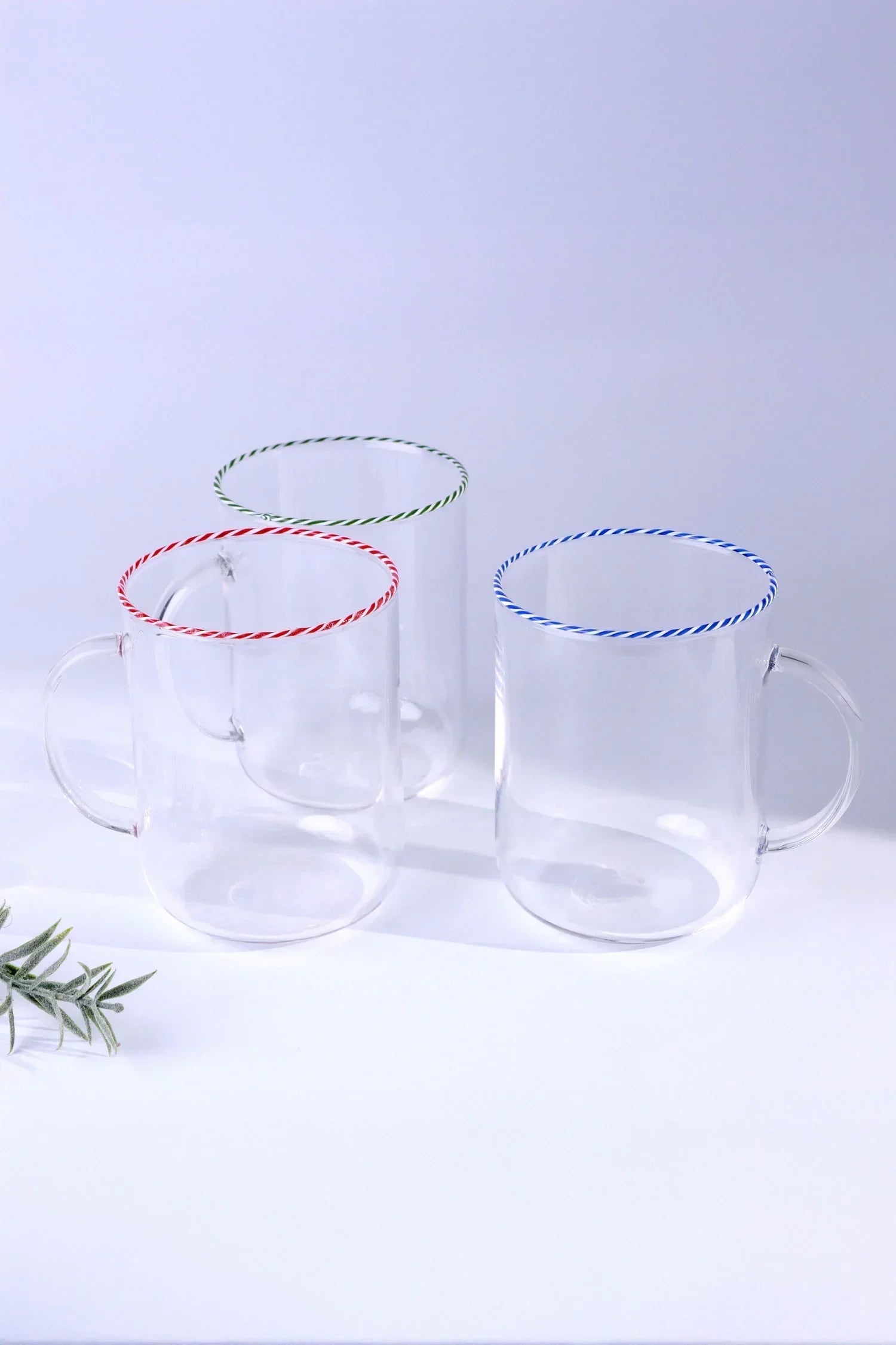 Set of three clear glass mugs with red, green, and blue twisted rims on white background, G Decor luxury tableware.