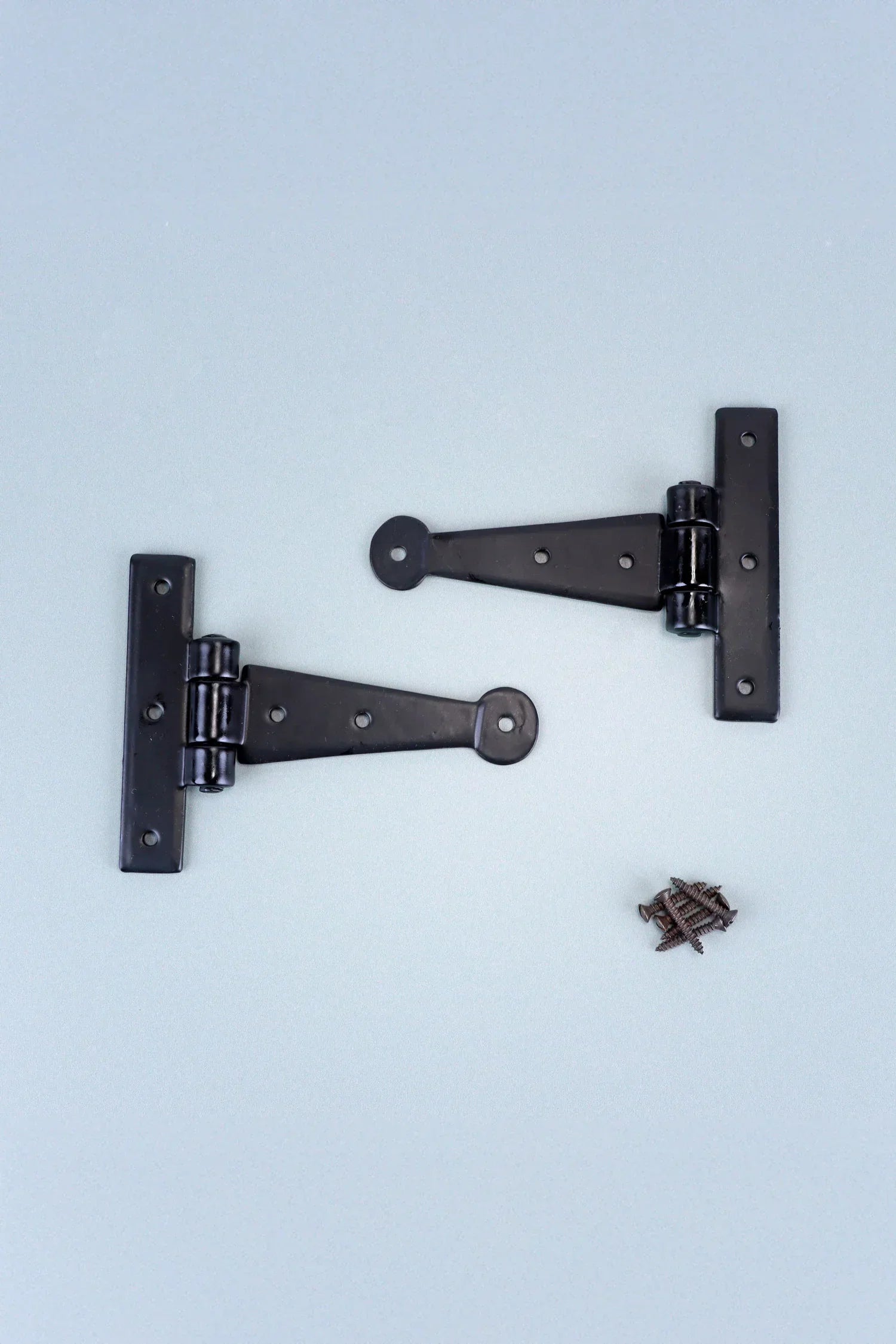 Black metal T hinges with matching screws on a light surface, luxury hardware by G Decor