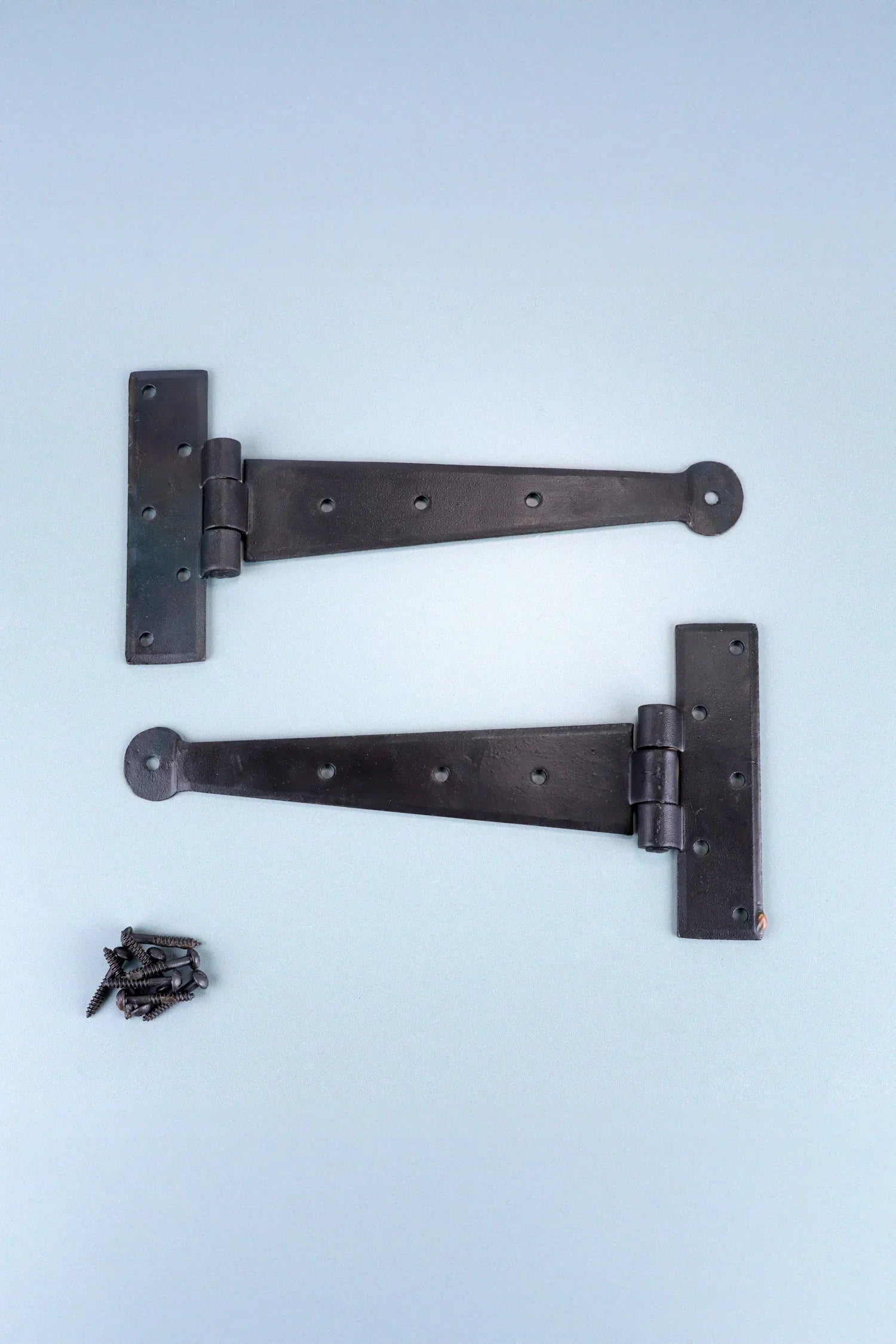 Pair of black decorative T-hinges with screws on a light surface, G Decor luxury hardware