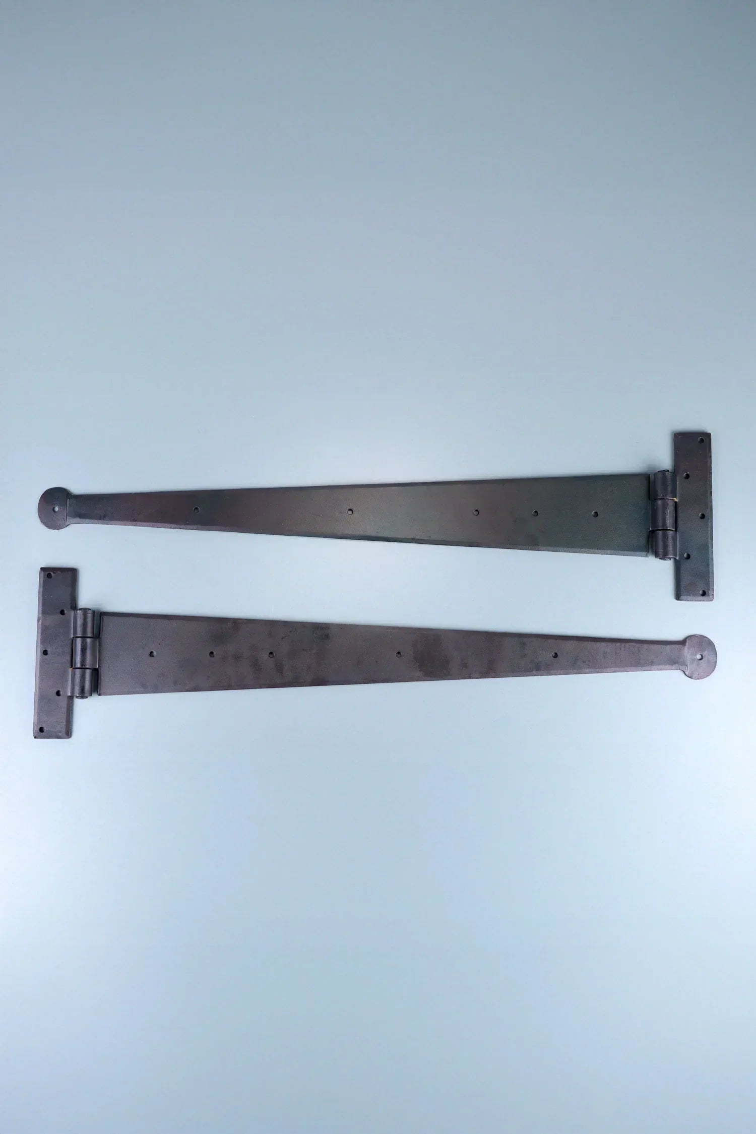 Two black metal strap hinges for doors or cabinets on a light blue background, G Decor hardware