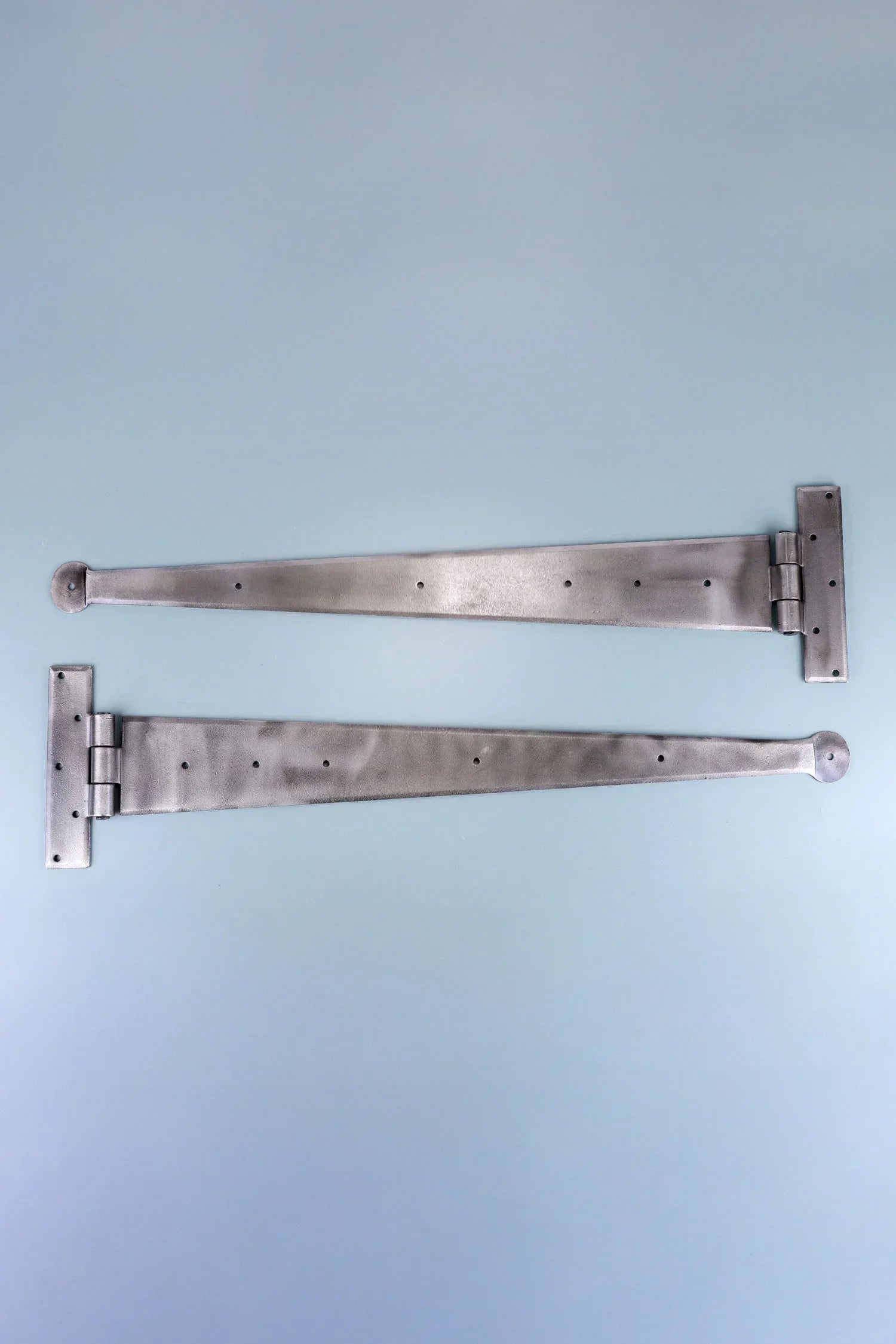 Pair of silver metal T-hinges for doors or cabinets on a light blue background, G Decor hardware