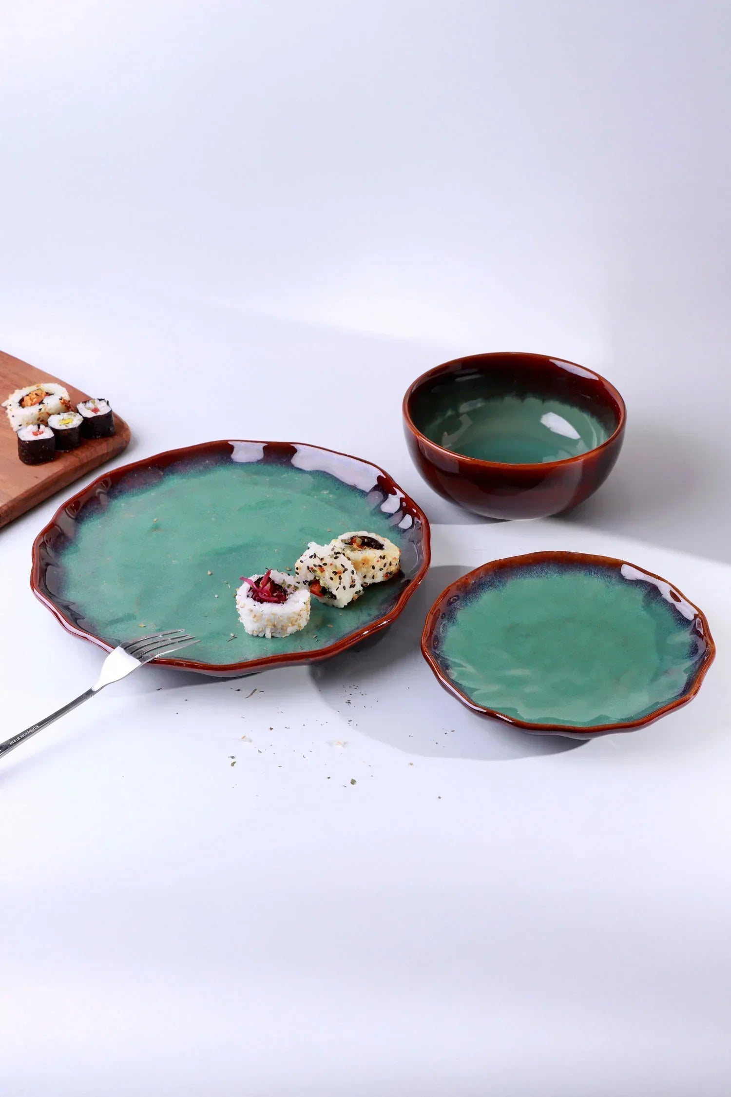 Green and brown ceramic dinnerware set by G Decor with sushi and bowl on a white background