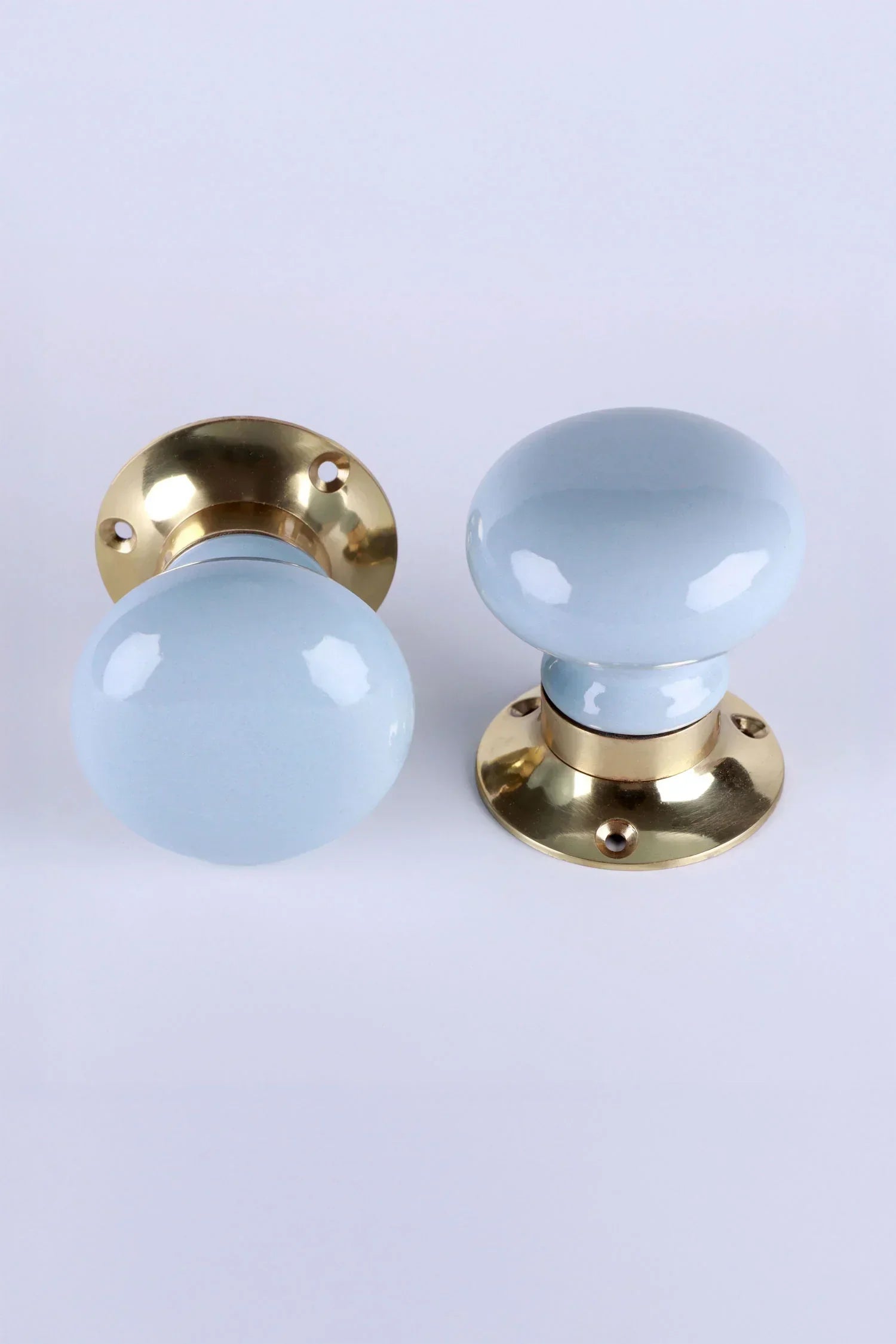 Pair of light blue ceramic door knobs with gold bases from G Decor luxury hardware collection