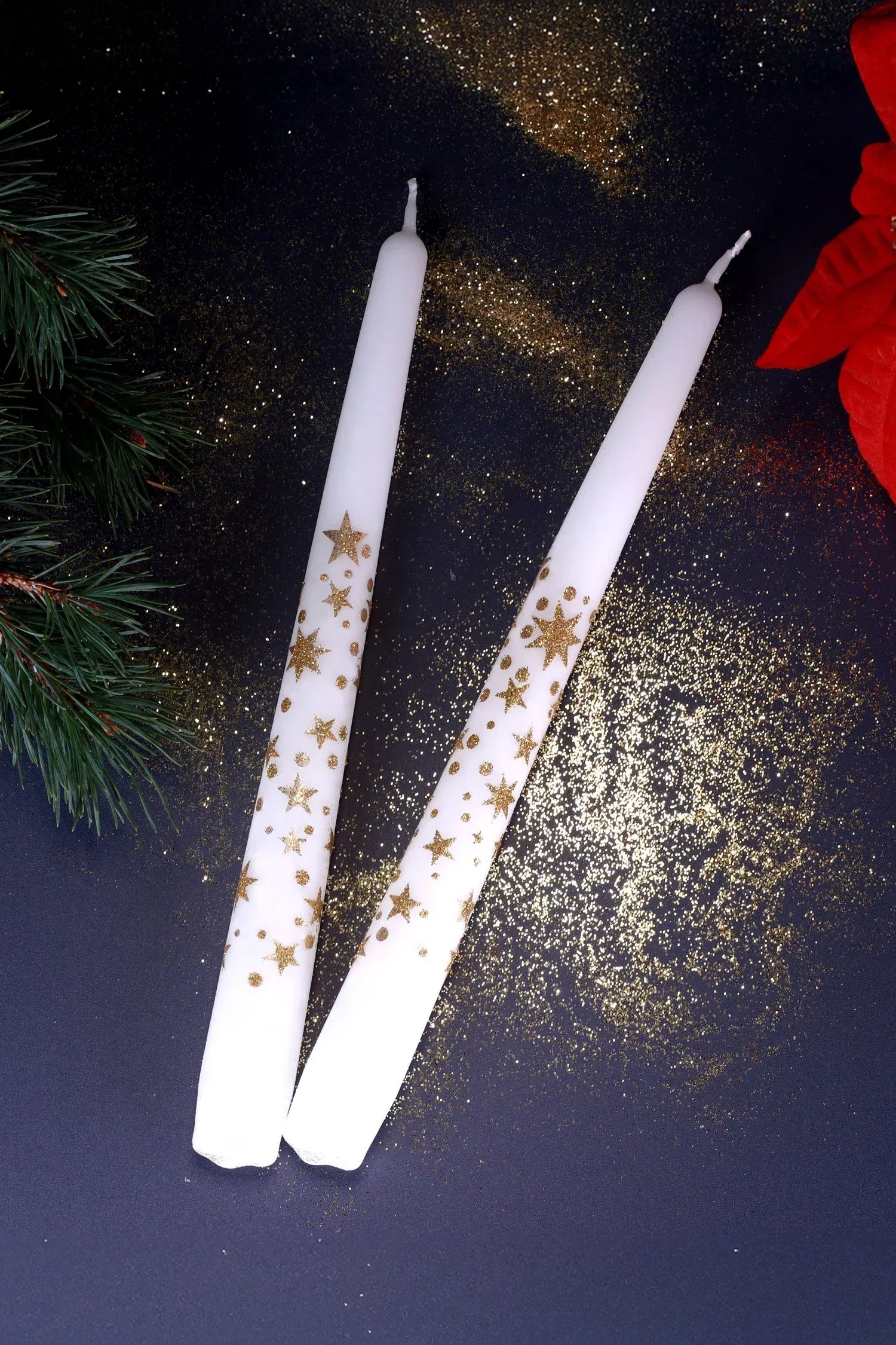 Pair of white taper candles with gold star glitter, festive decor on dark background from G Decor.