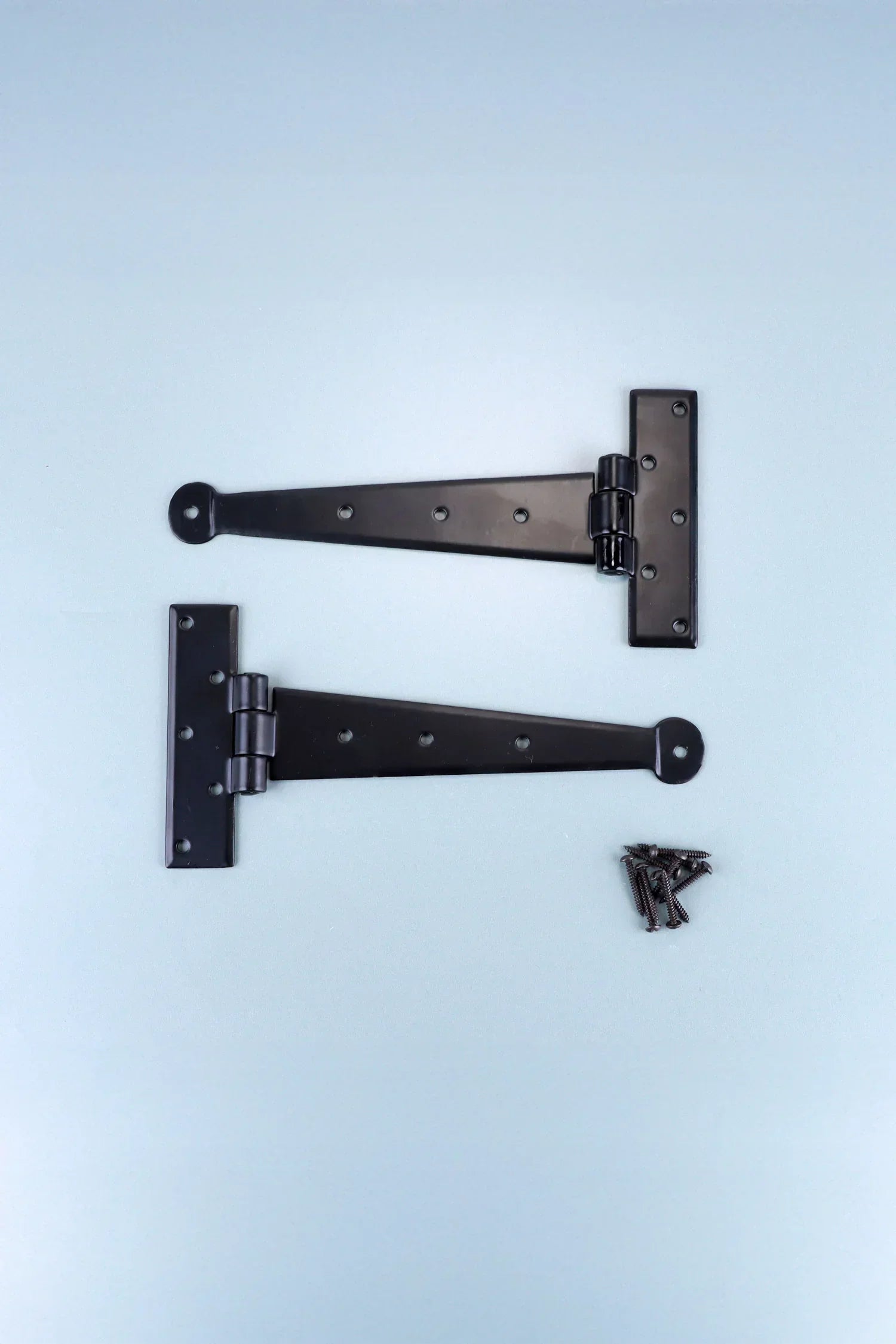 Pair of black T hinge brackets with screws, G Decor luxury hardware on light blue background.