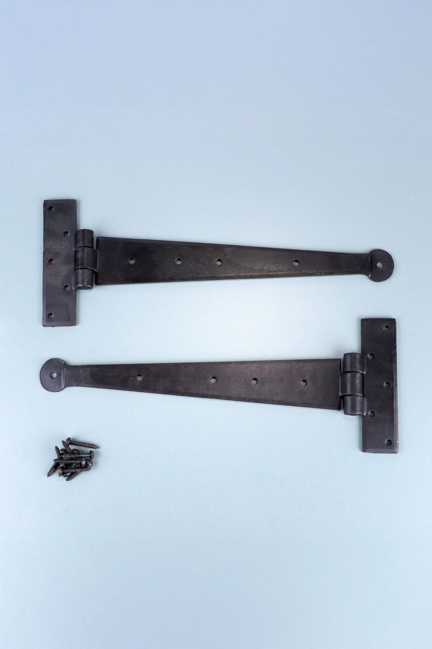 Pair of black metal T-hinges with screws, hardware from G Decor on a light background.
