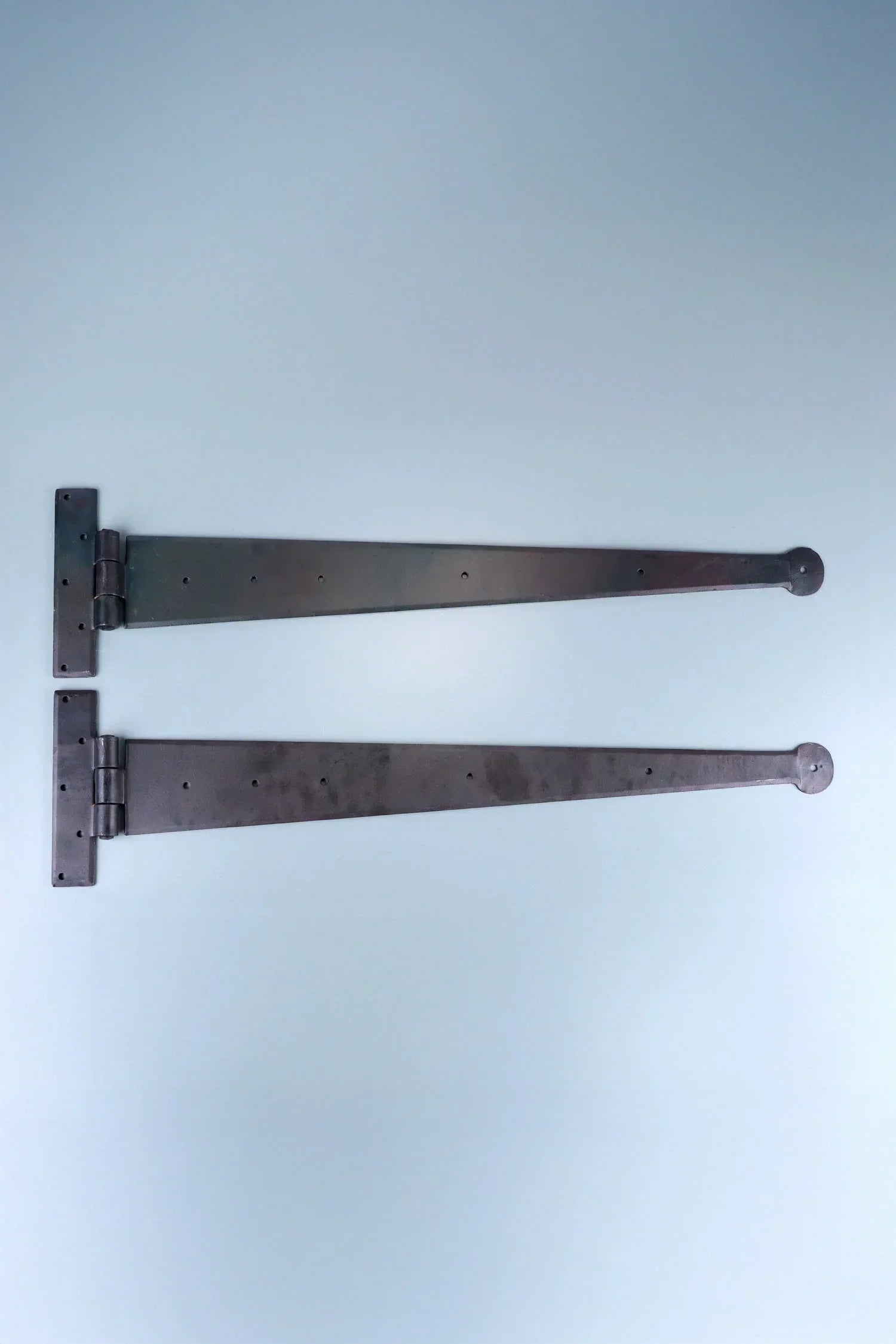 Pair of black metal strap hinges for doors or gates, displayed on a light background