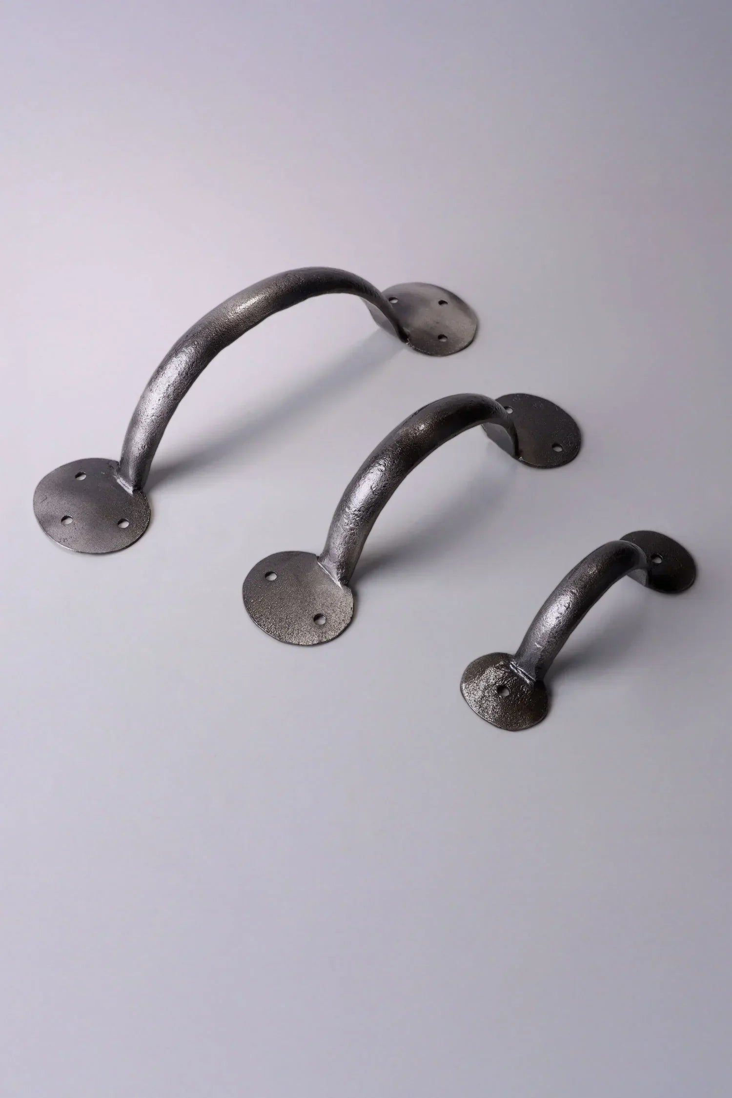 Three metal cabinet handles with round bases from G Decor, displayed on a light surface.