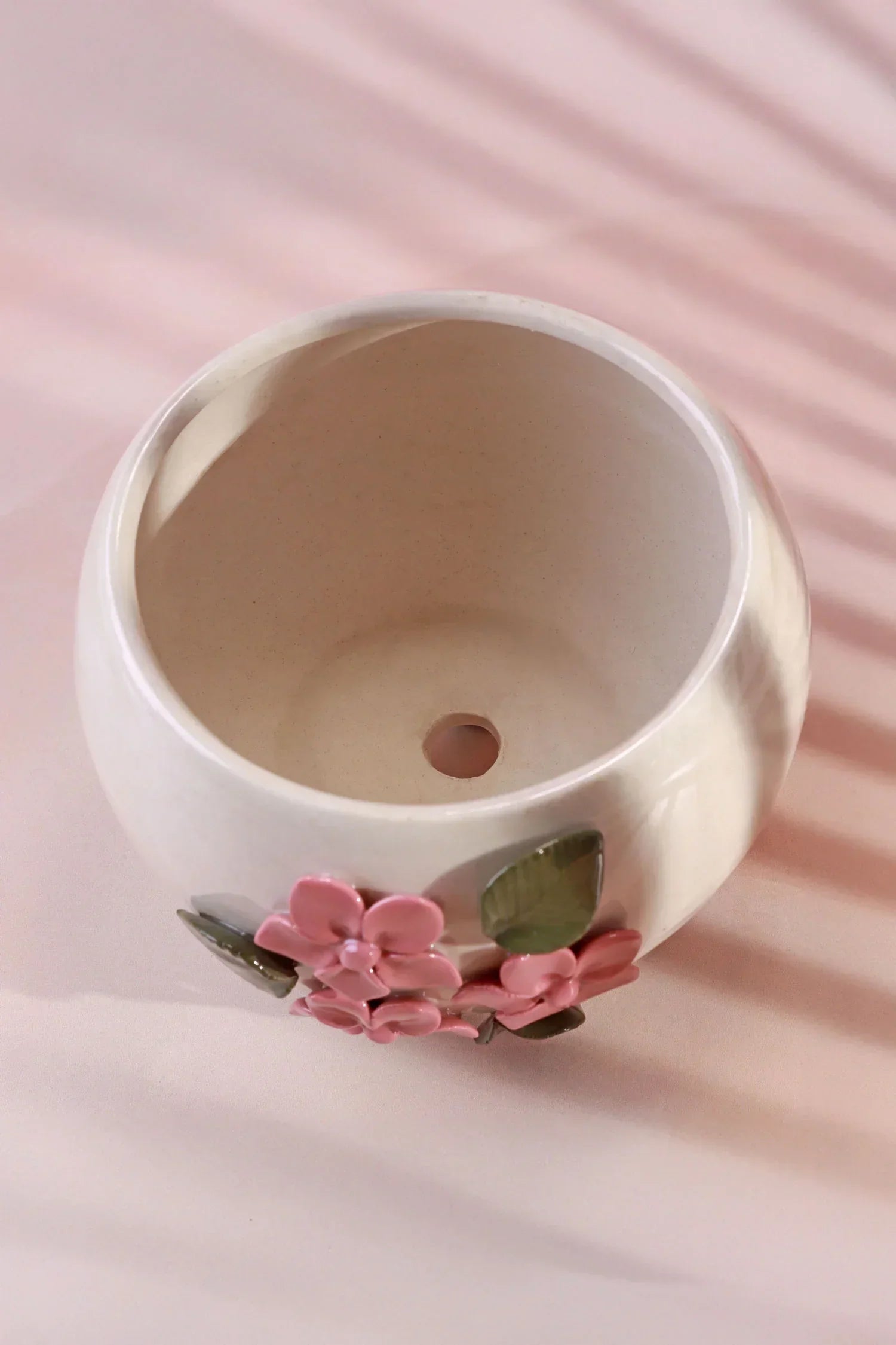 Ceramic flower pot with pink floral decor and drainage hole on a soft pink background, G Decor