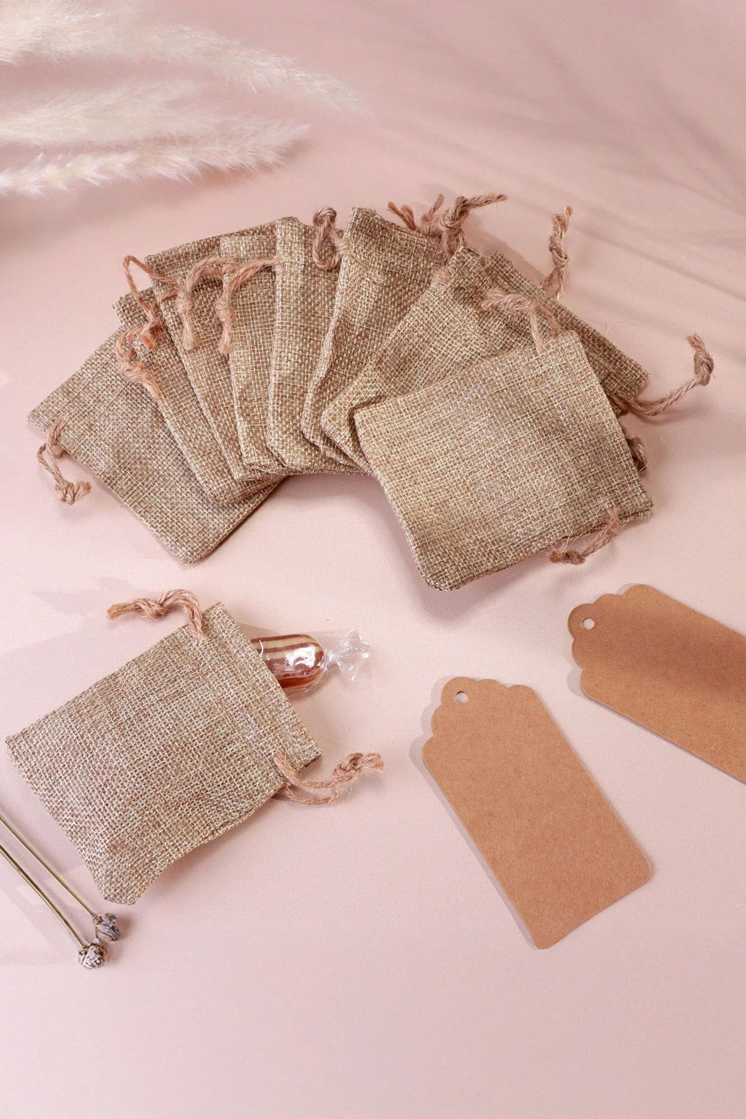 Rustic burlap gift bags with drawstrings and kraft tags on a soft pink background, G Decor