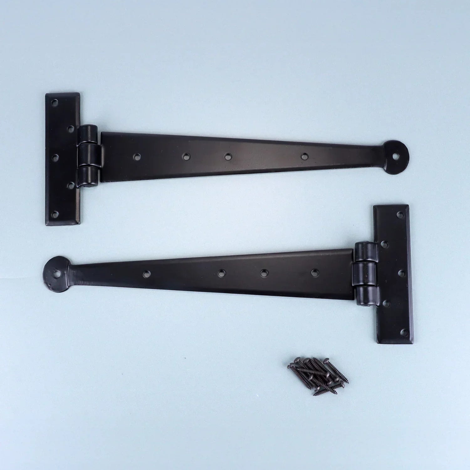 Pair of black metal T hinges with screws on light background, G Decor hardware.