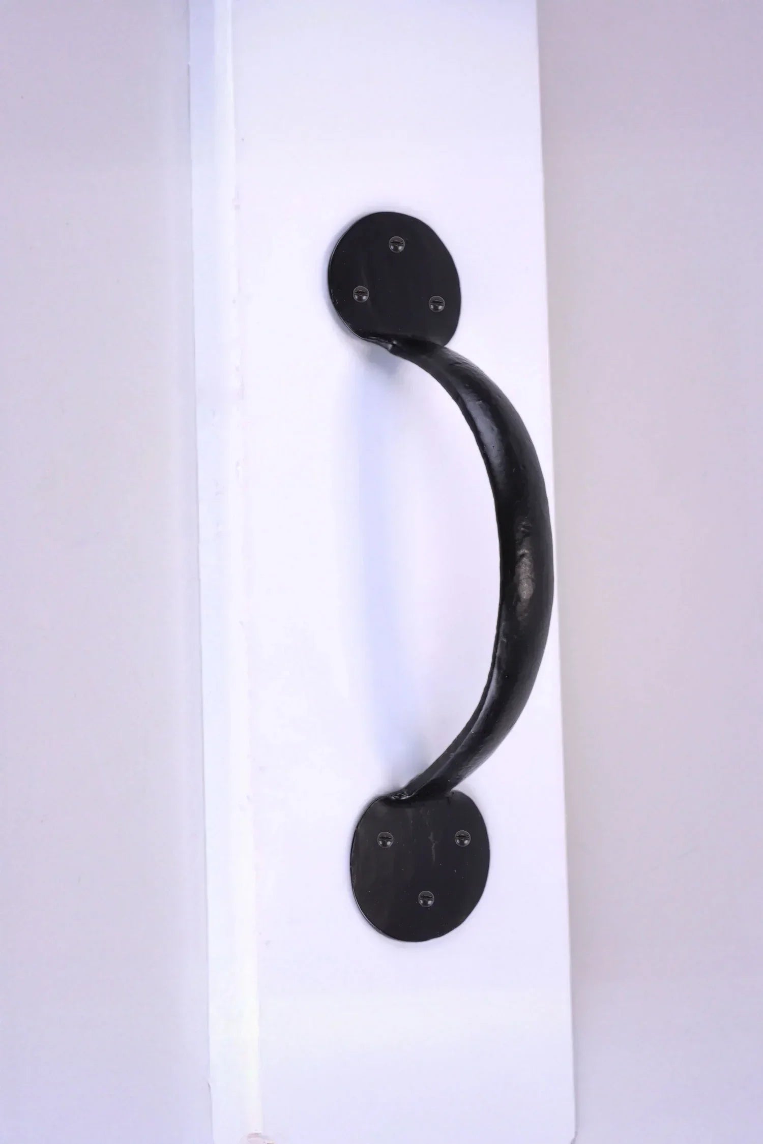 Black metal door handle on white surface, luxury hardware by G Decor
