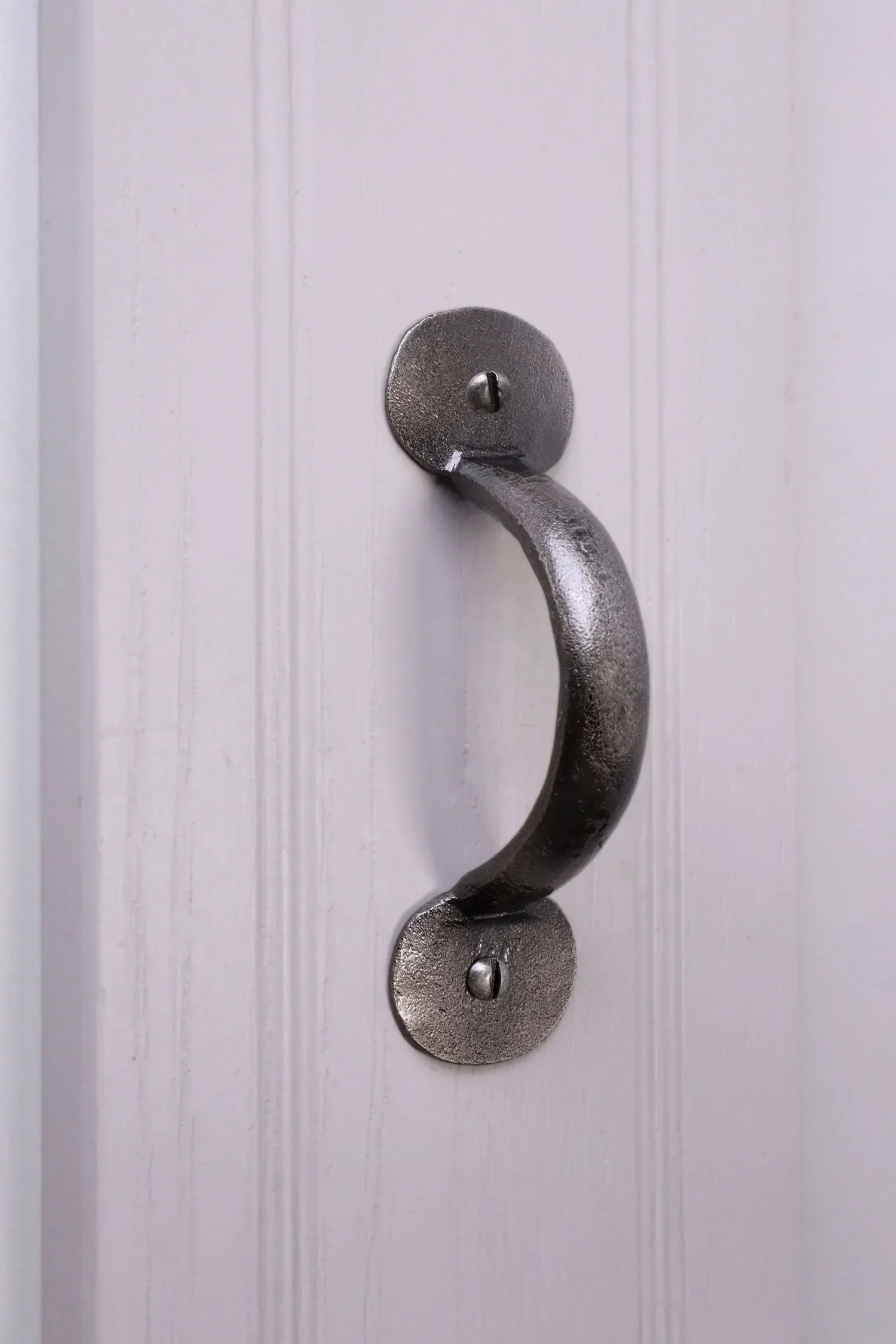 Silver metal cabinet pull handle on a white paneled door, G Decor luxury hardware
