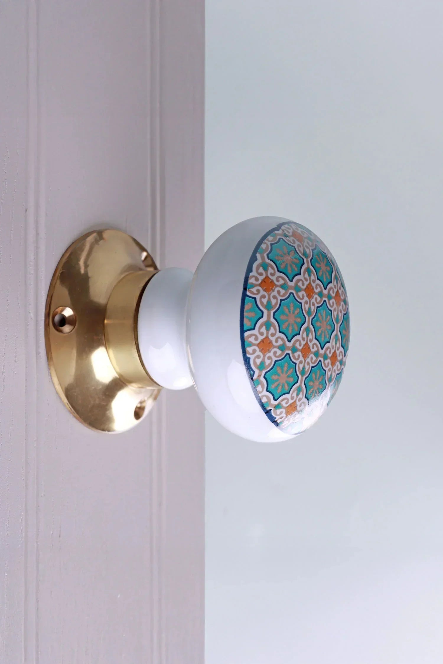 Decorative ceramic door knob with gold base and intricate blue and orange pattern by G Decor