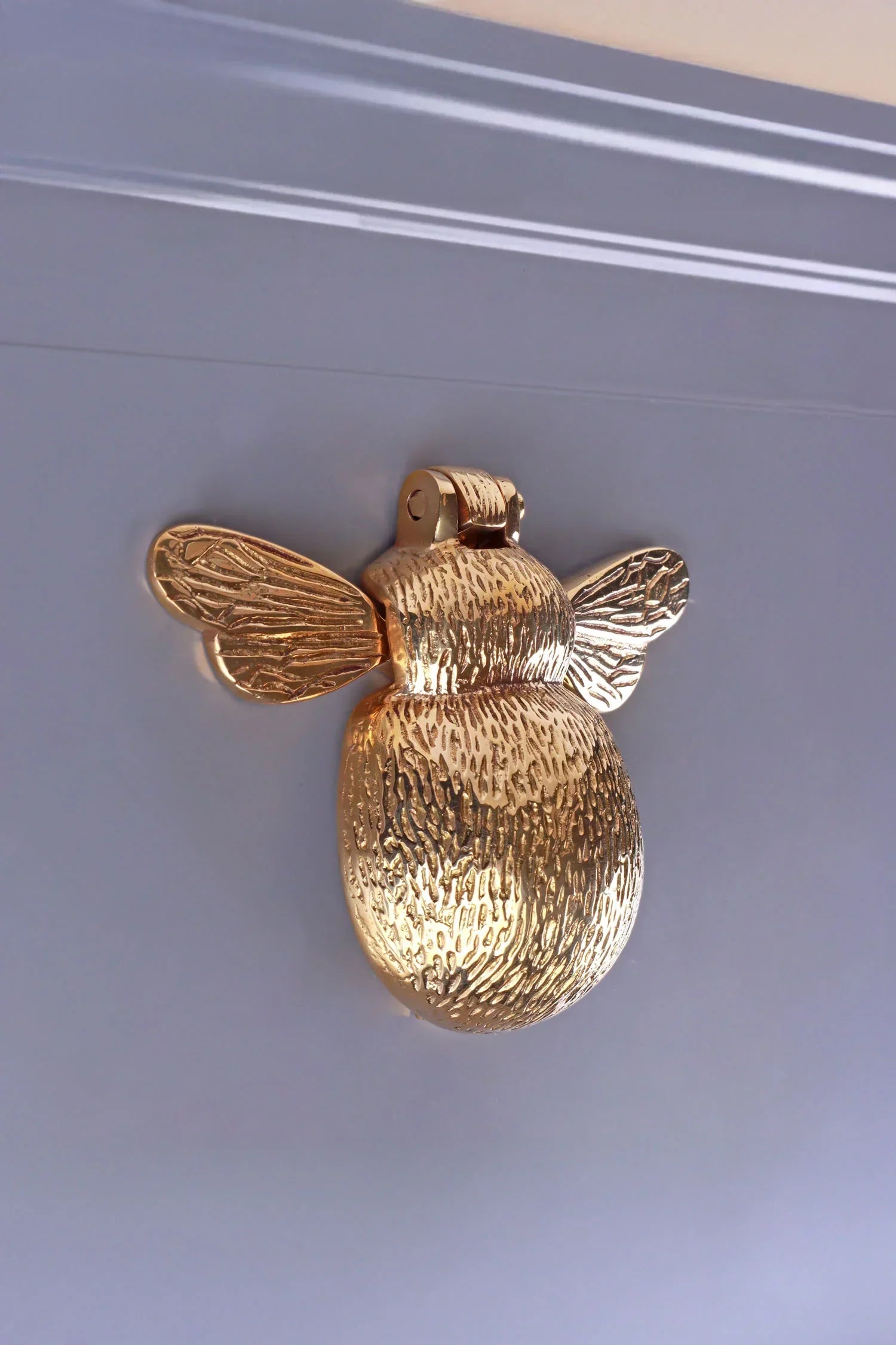 Gold bee-shaped luxury hardware door knocker on a grey door, G Decor home décor.