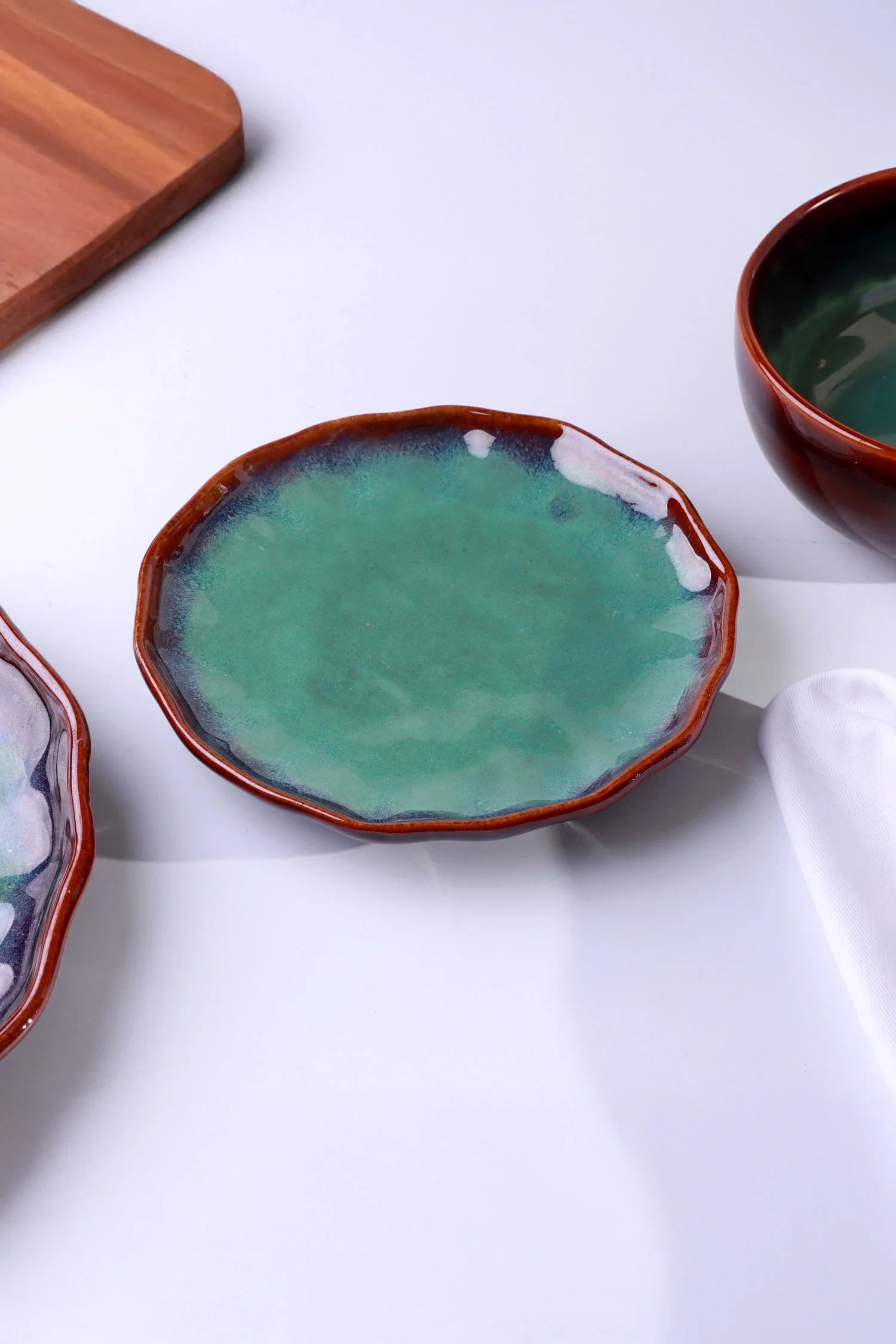 Handcrafted ceramic plate with green glazed center and brown rim on white background, G Decor tableware