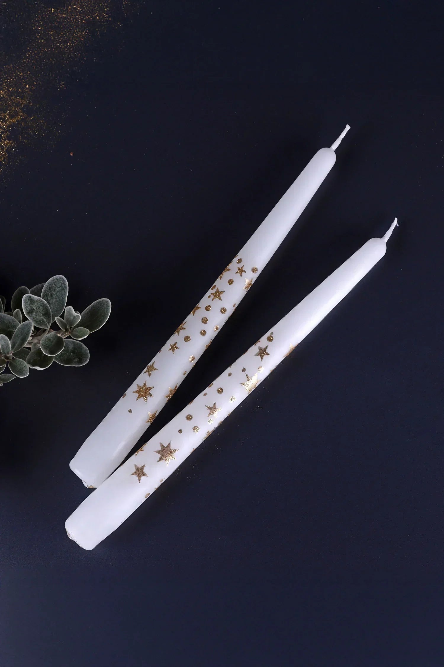 White taper candles with gold star designs from G Decor, styled on a dark background