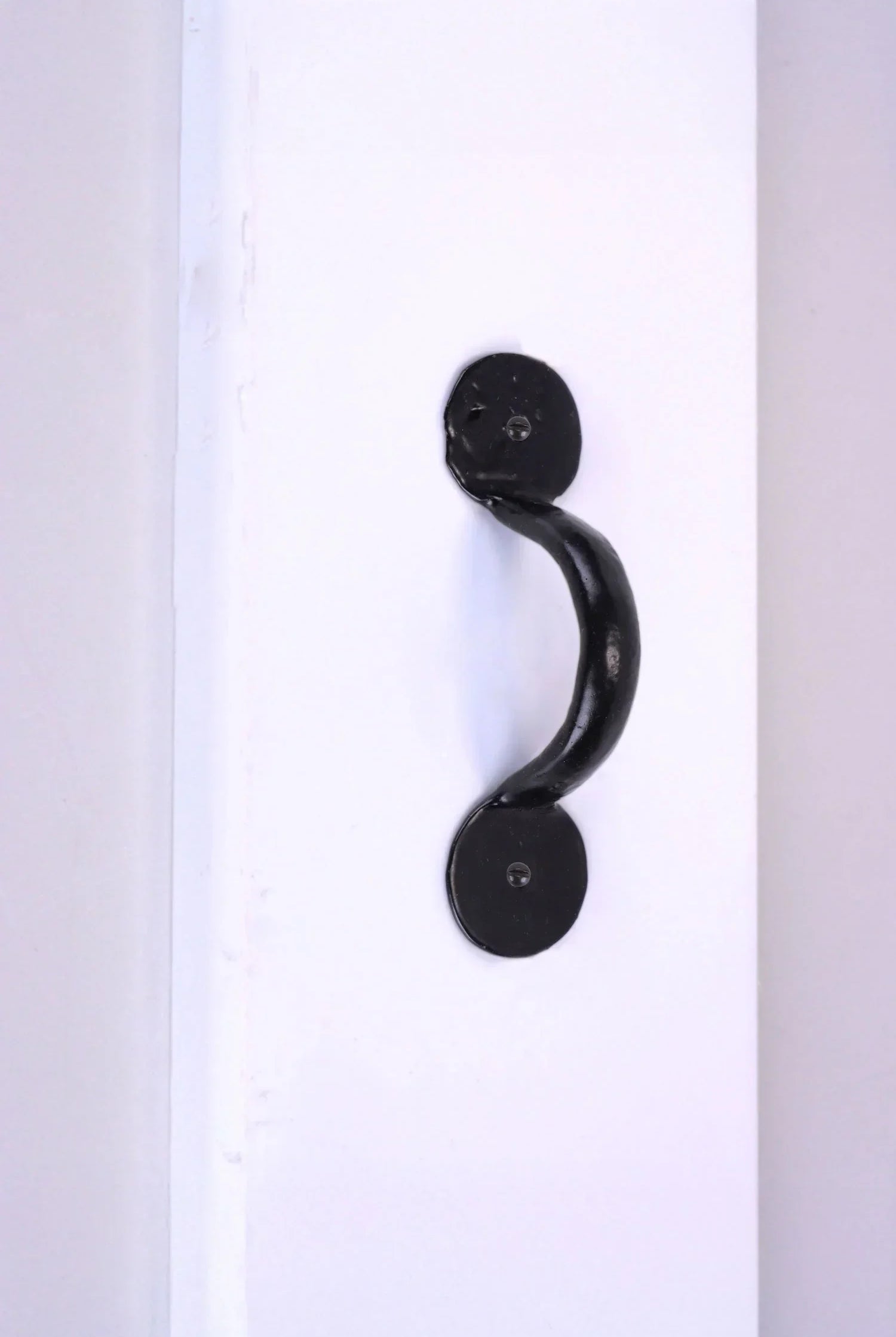 Black metal door pull handle on white panel by G Decor luxury hardware