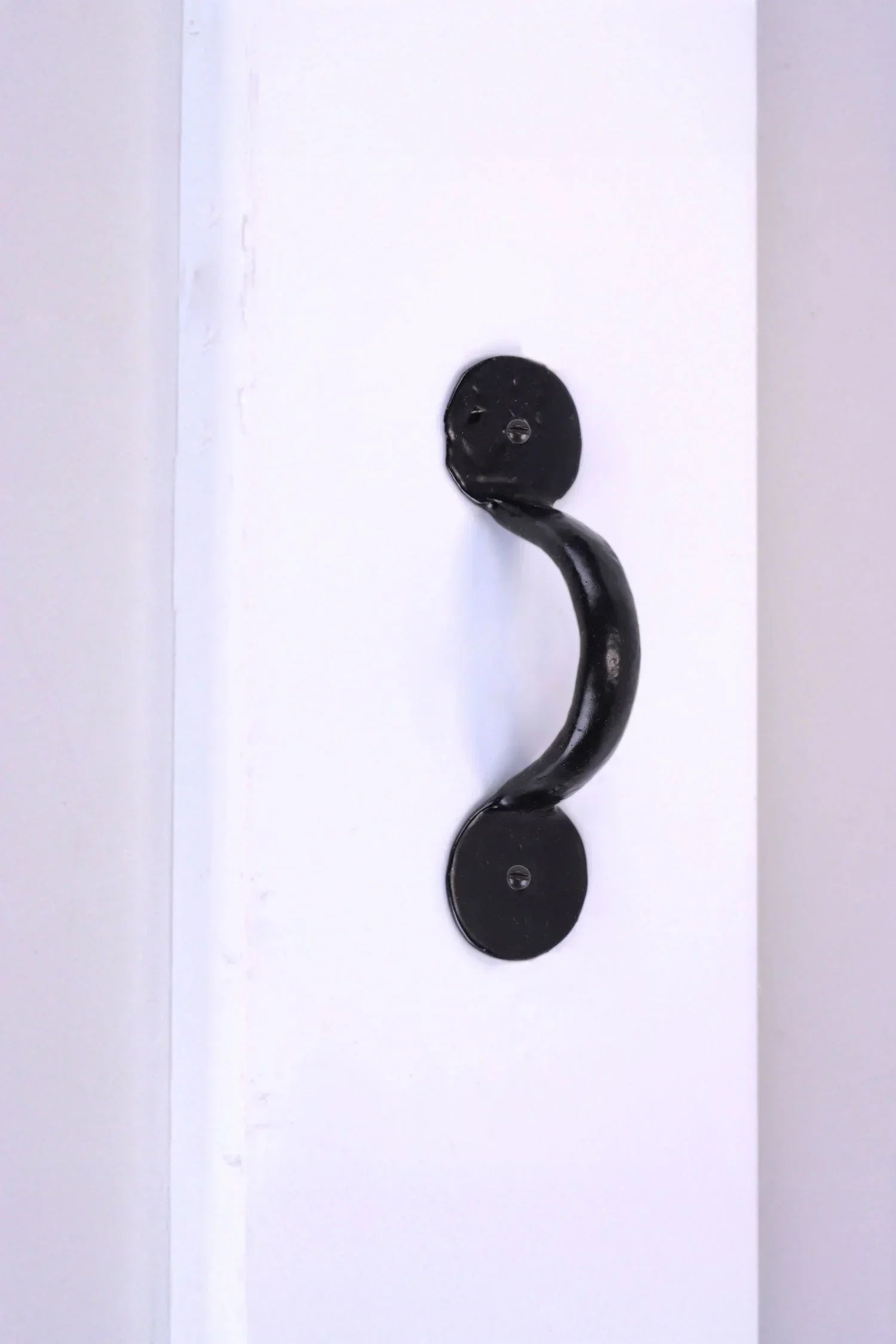 Black metal door pull handle on white panel by G Decor luxury hardware