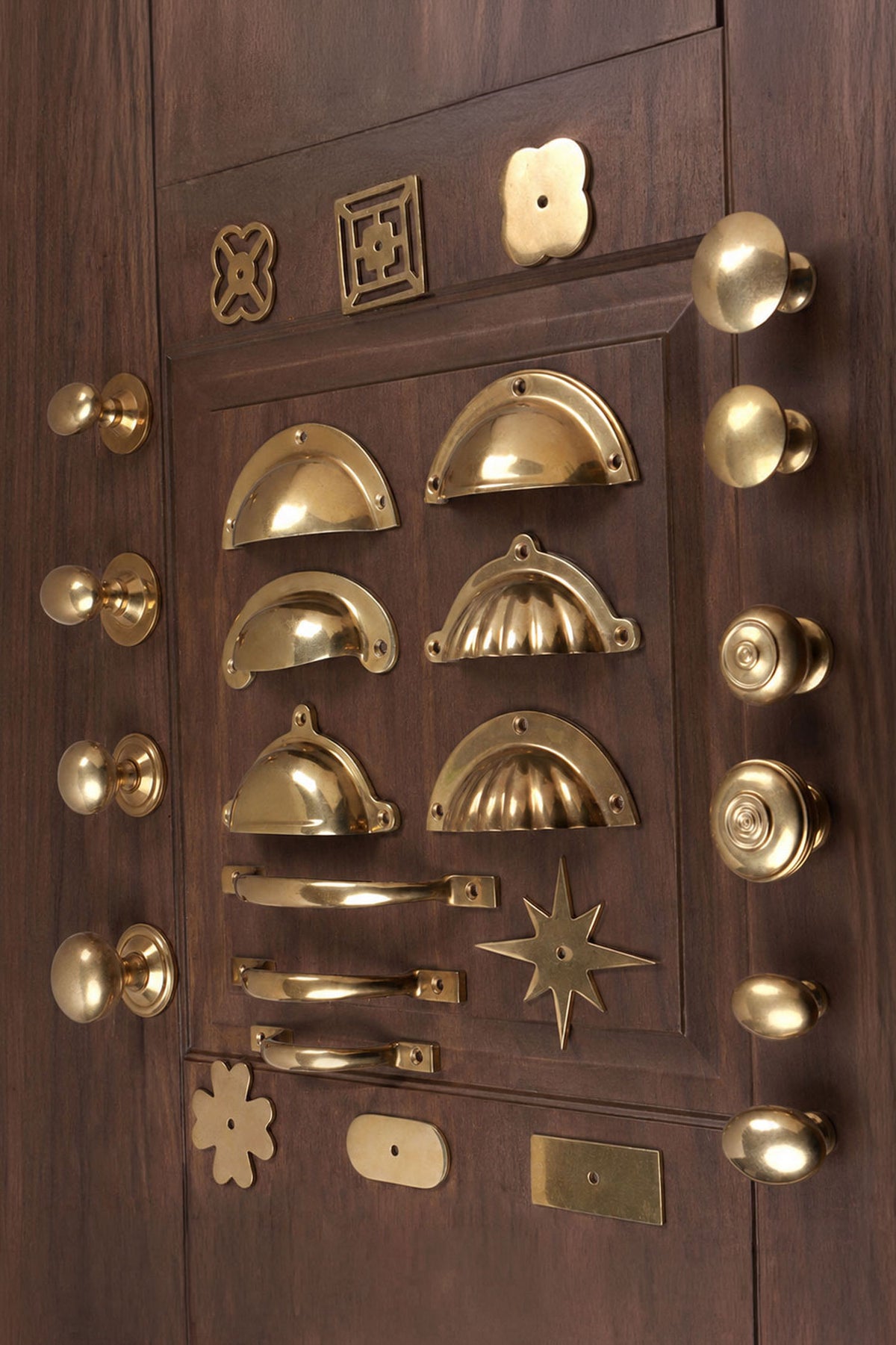 Angled view of the aged brass knobs, cup pulls, D handles and backplates on a panelled door