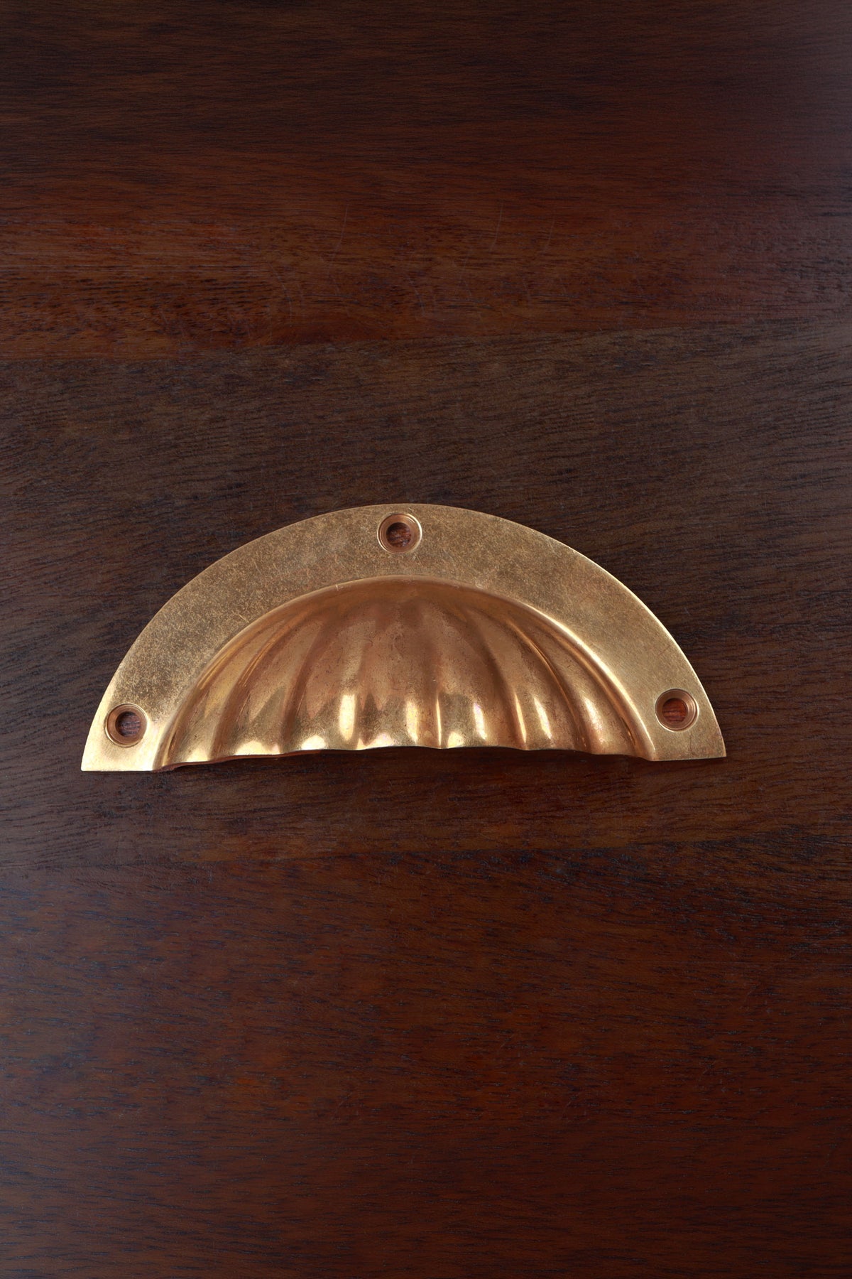 Fluted aged brass cup pull on a half-moon plate