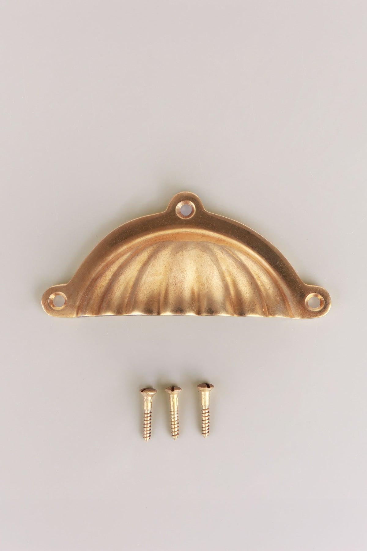 Scalloped aged brass cup pull with its screws