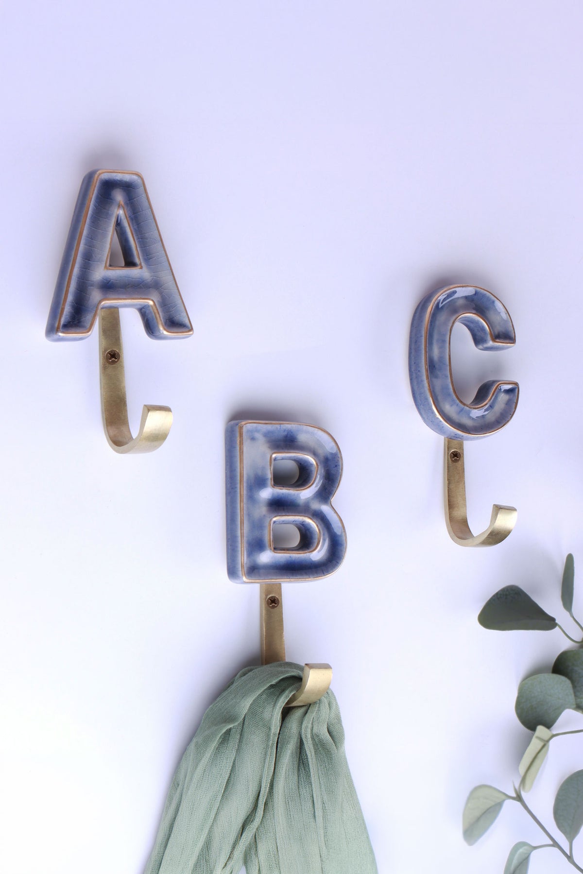Blue ceramic letter wall hooks with gold rims on gold-tone hooks