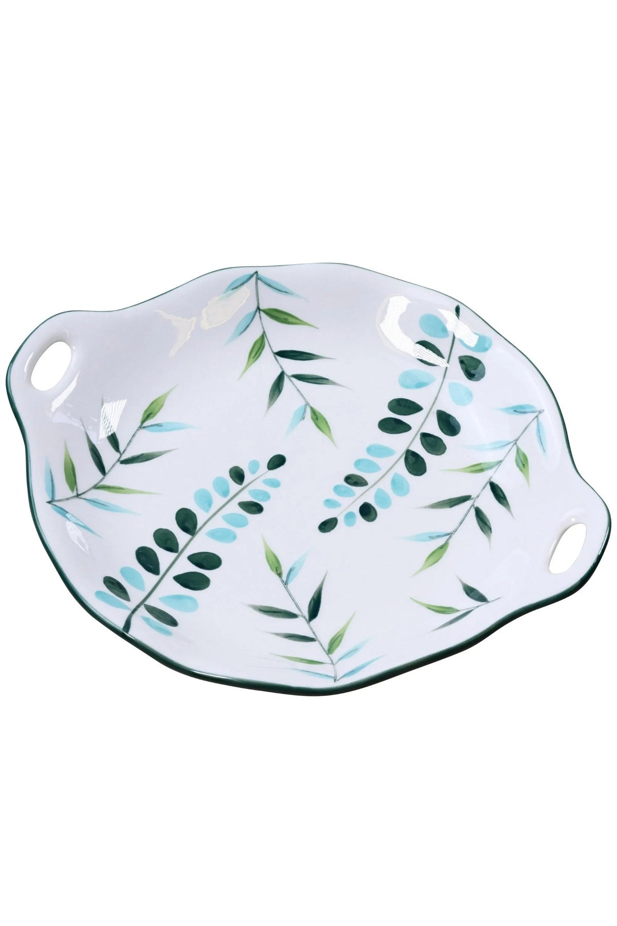 Round white ceramic serving plate with green and blue leaves and two cut-out handles, on white