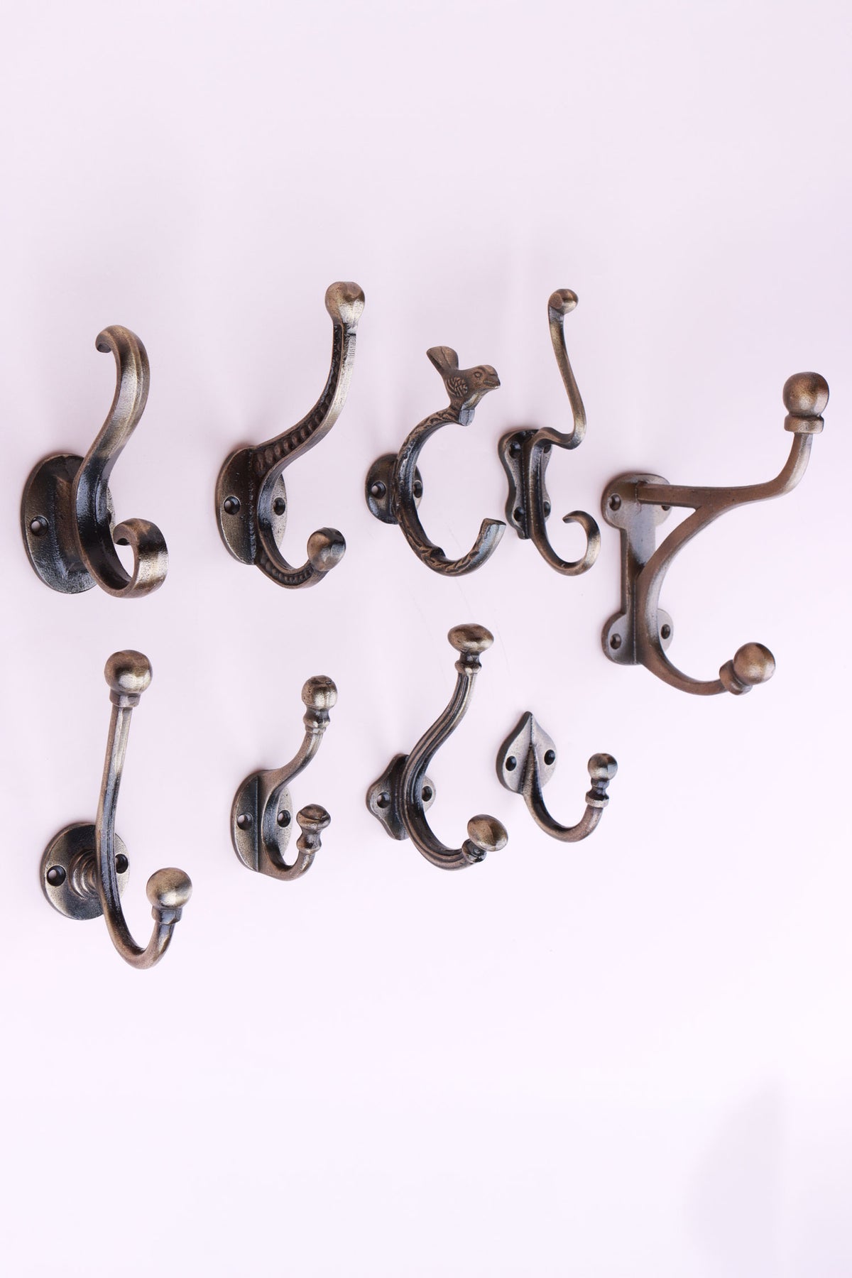 The nine cast iron hooks in antique brass finish set out in rows of three, seen from the side