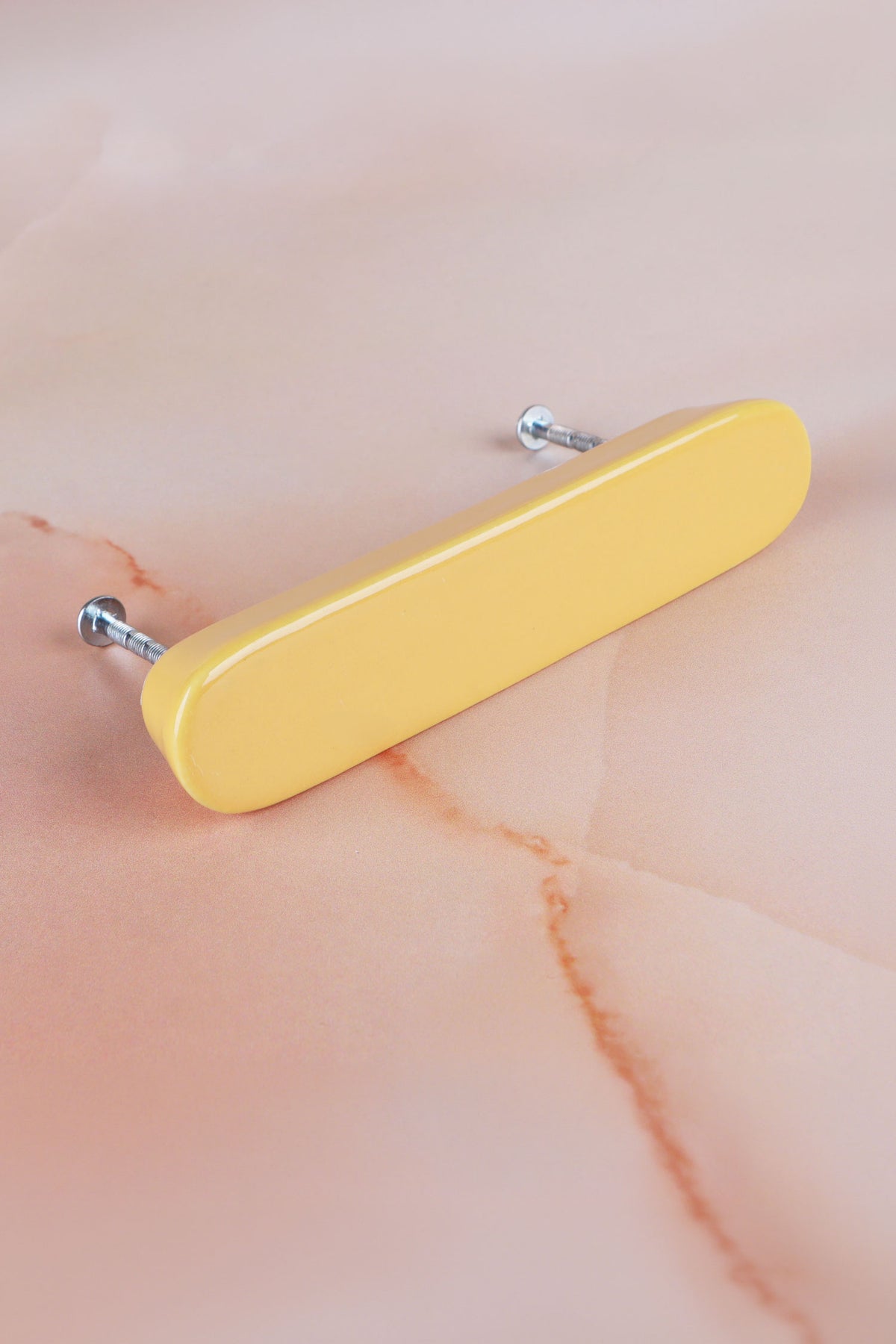 Yellow ceramic bar handle, a warm butter yellow, with its two fixing bolts